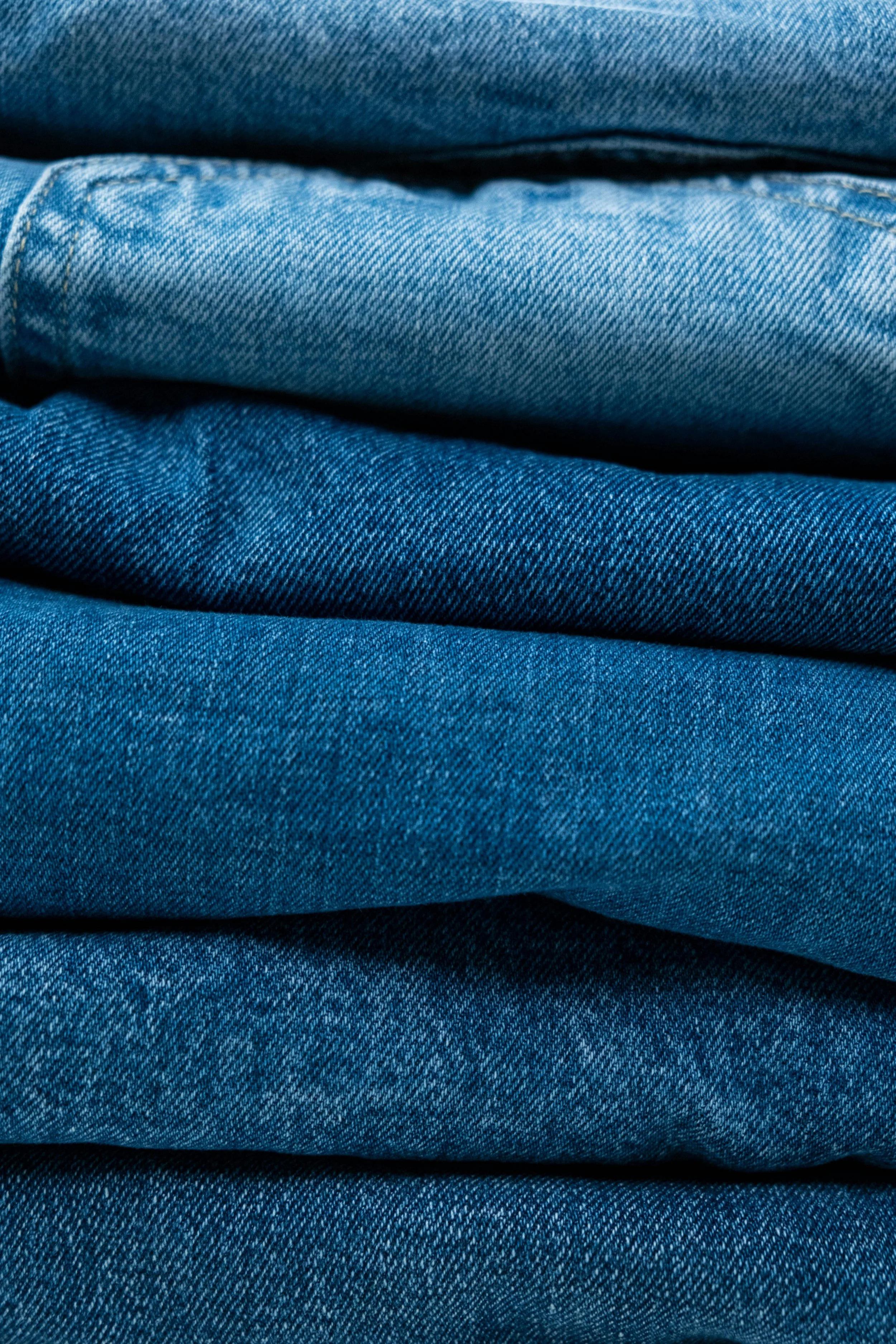 Stacked blue denim jeans in various shades.