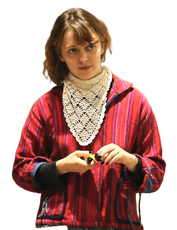 A young woman with short, light brown hair wearing a red plaid jacket and a white crocheted scarf, holding a small yellow and black toy car, looking to the side with a neutral expression.