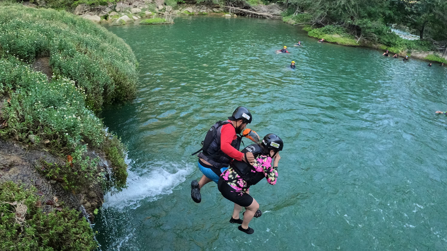Dos personas con cascos y mochilas saltando desde una cascada de San Luis Potosi.
