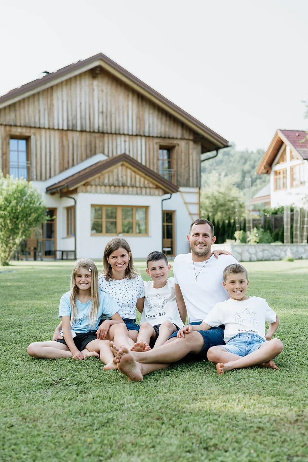 Familienfotograf Salzkammergut - Eine glückliche Familie sitzend auf einer Wiese im Garten