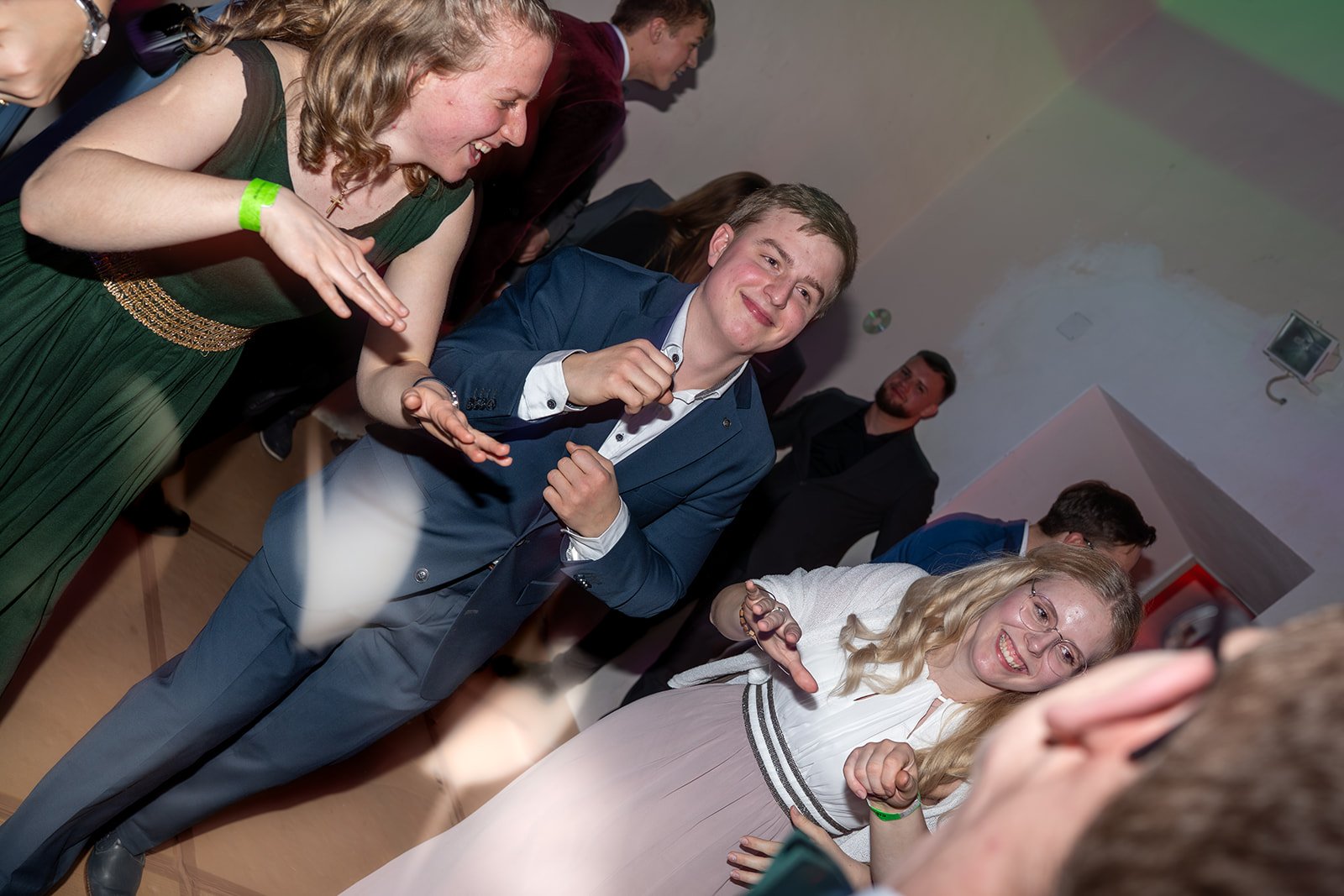 Menschen tanzen und lachen auf einer Party im festlichen Outfit.