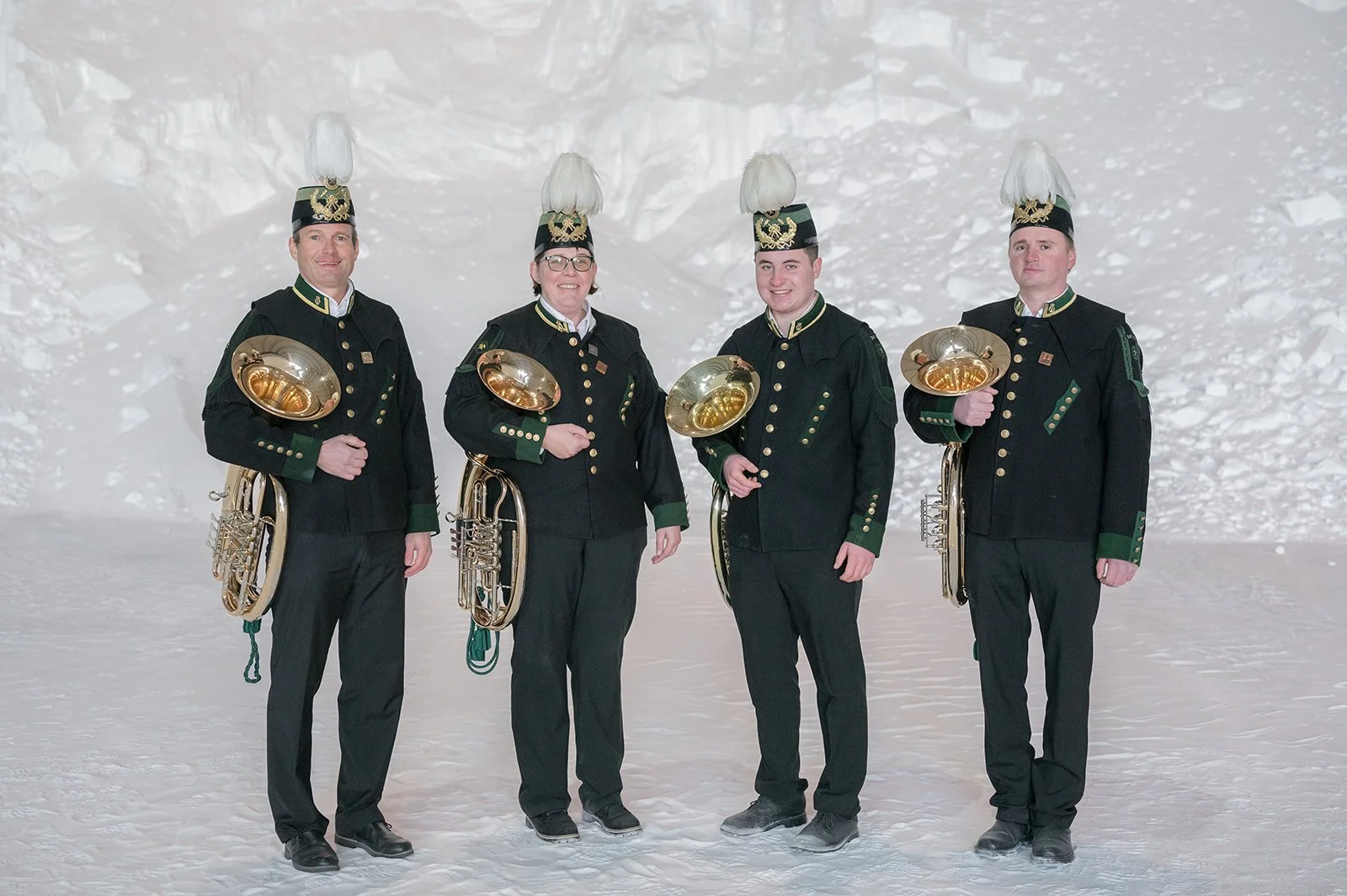 Fünf Musiker in historischer Tracht mit Hüten und Musikinstrumenten, stehend auf Schnee in einer Bunker- oder Eishöhle