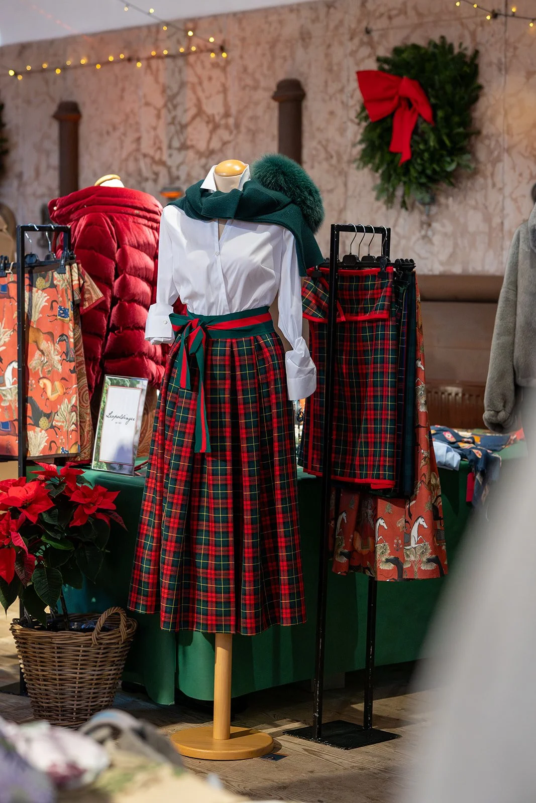 Verkaufstresen mit Weihnachtsdekoration, darunter eine Poinsettia-Pflanze, und ein Schaufenster mit herbstlicher Dekoration, zur Weihnachtszeit passend.