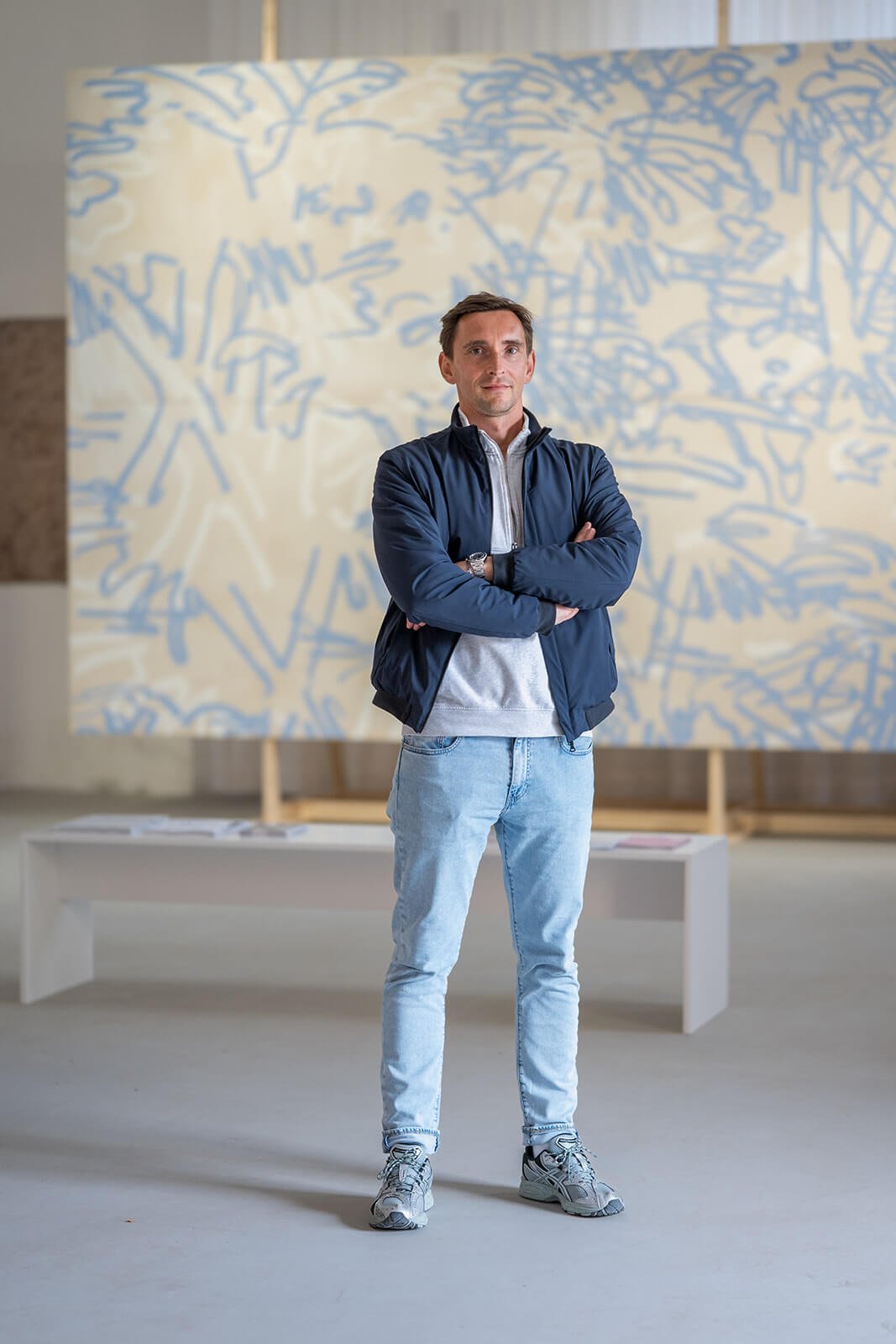 Künstlerportrait von Peter Jellitsch im Hintergrund sieht man eine Gemälde