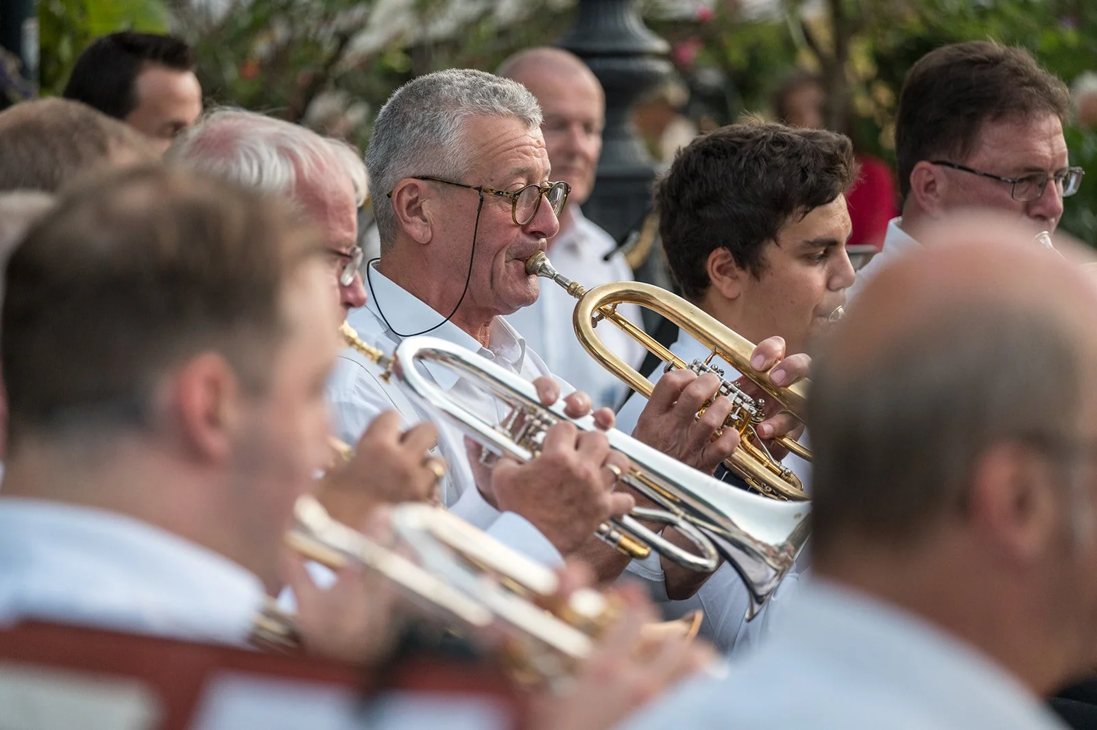 Musiker in einer Gruppe, die Blechblasinstrumente wie Trompeten und Posaunen spielen, bei einem Outdoor-Konzert