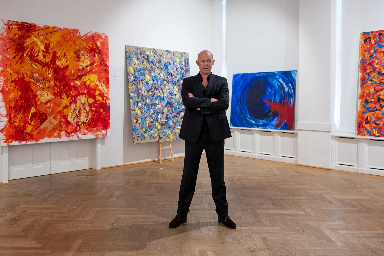 Künstlerportrait von Pablo Meier-Schomburg in der Trinkhalle Bad Ischl – der Maler steht vor seinen großformatigen abstrakten Gemälden während der Vernissage.