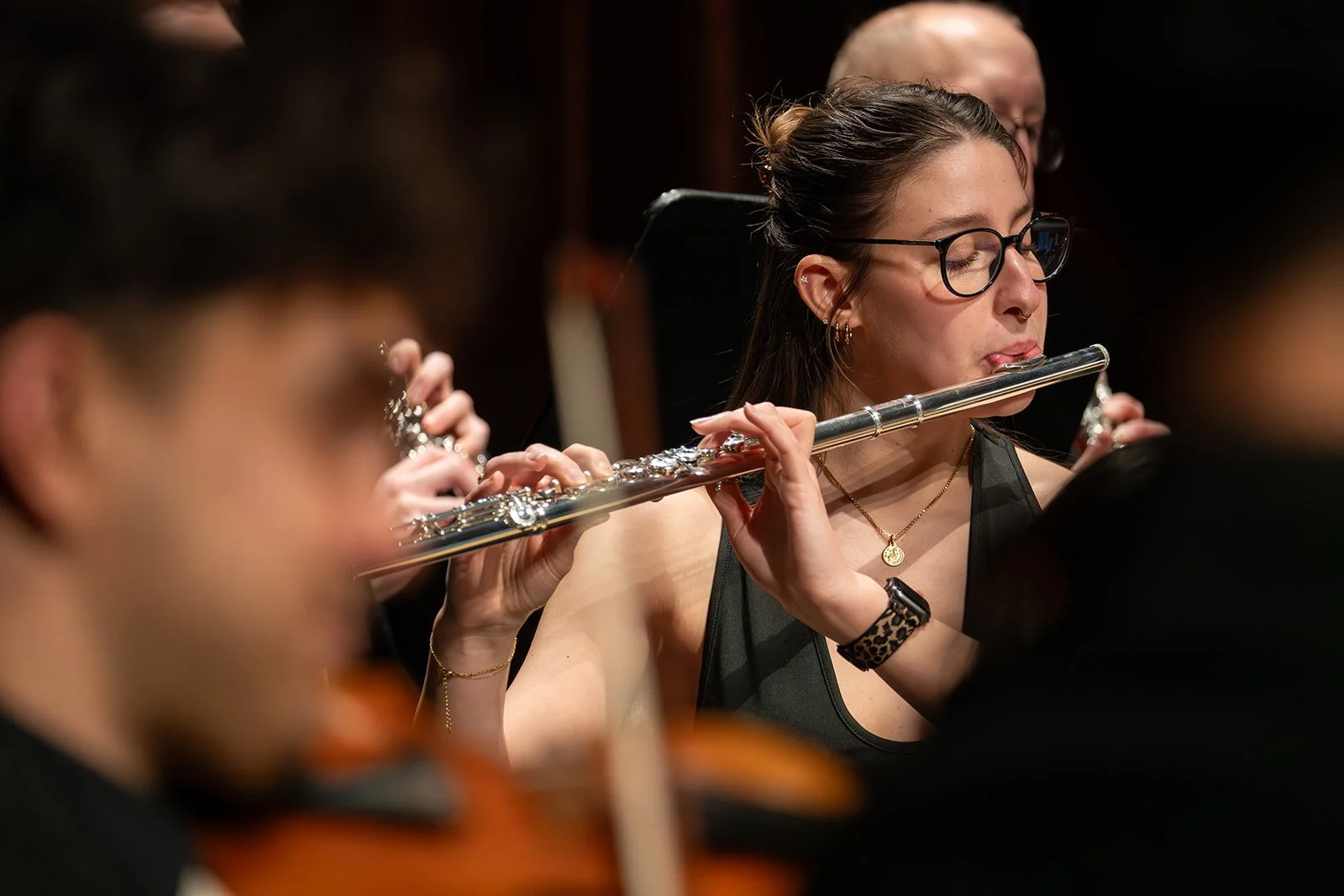 Frau spielt Flöte während eines Orchesters.