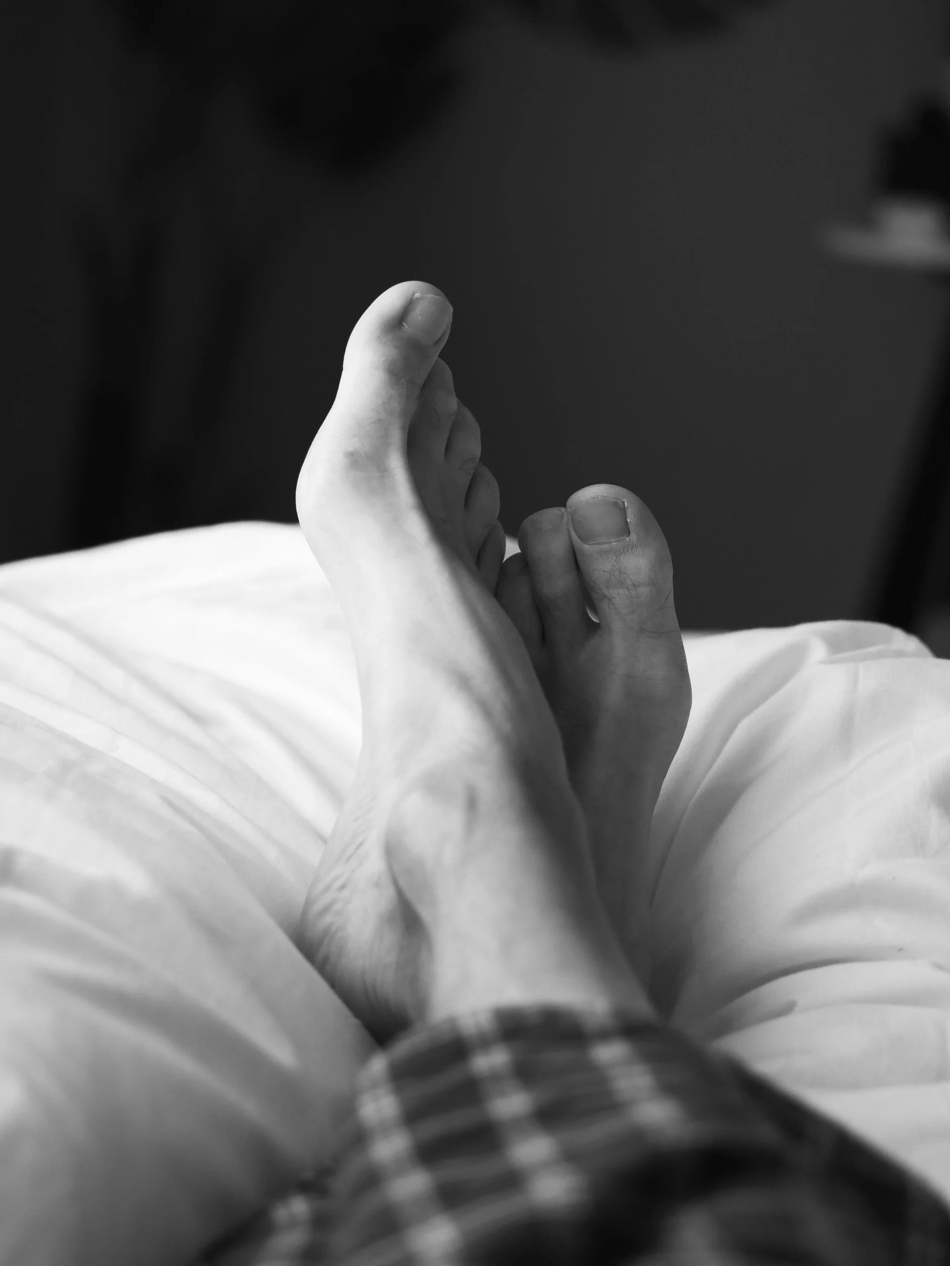 Relaxed feet resting on a bed, representing professional home visit podiatry care in Newport, Wales