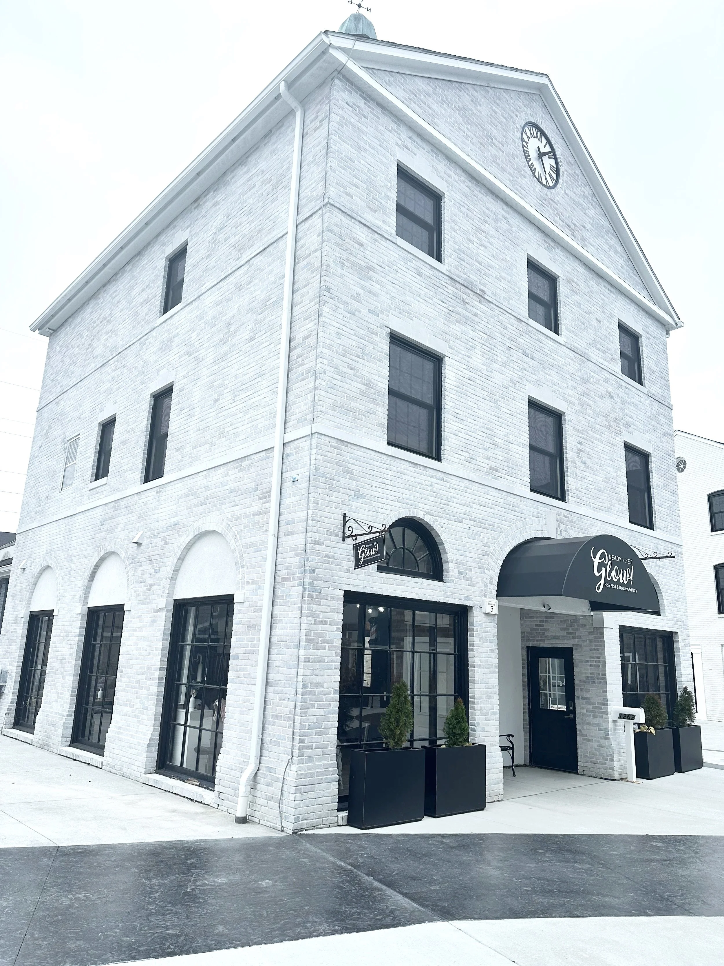White brick building with black signage and large windows with black frames.