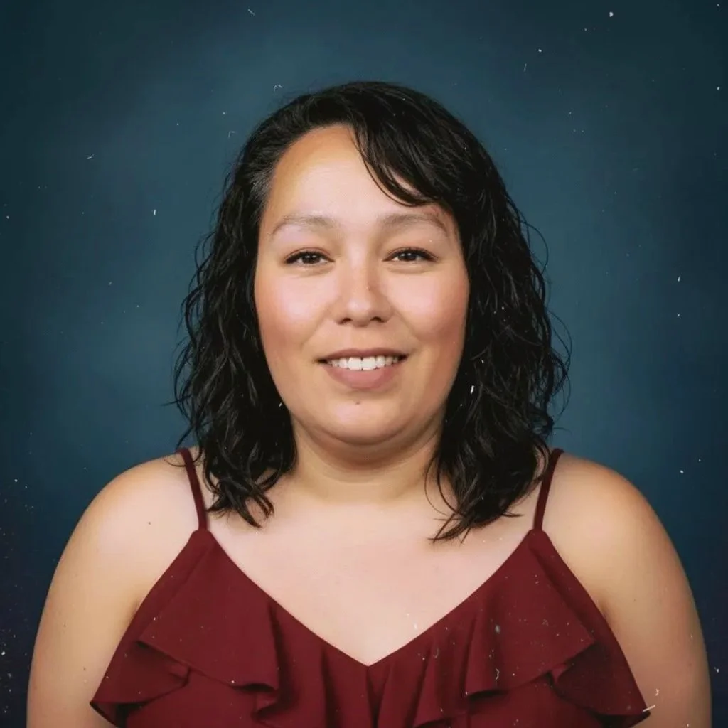 Portrait of Melissa Jordan with shoulder-length black curly hair, wearing a burgundy top with spaghetti straps, smiling, against a dark blue background with small white splashes.