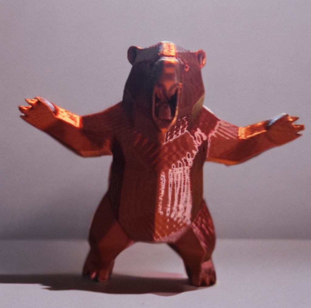 A bear sculpture made from rich, reddish-brown wood, standing on its hind legs with its front paws raised, set against a plain gray background.