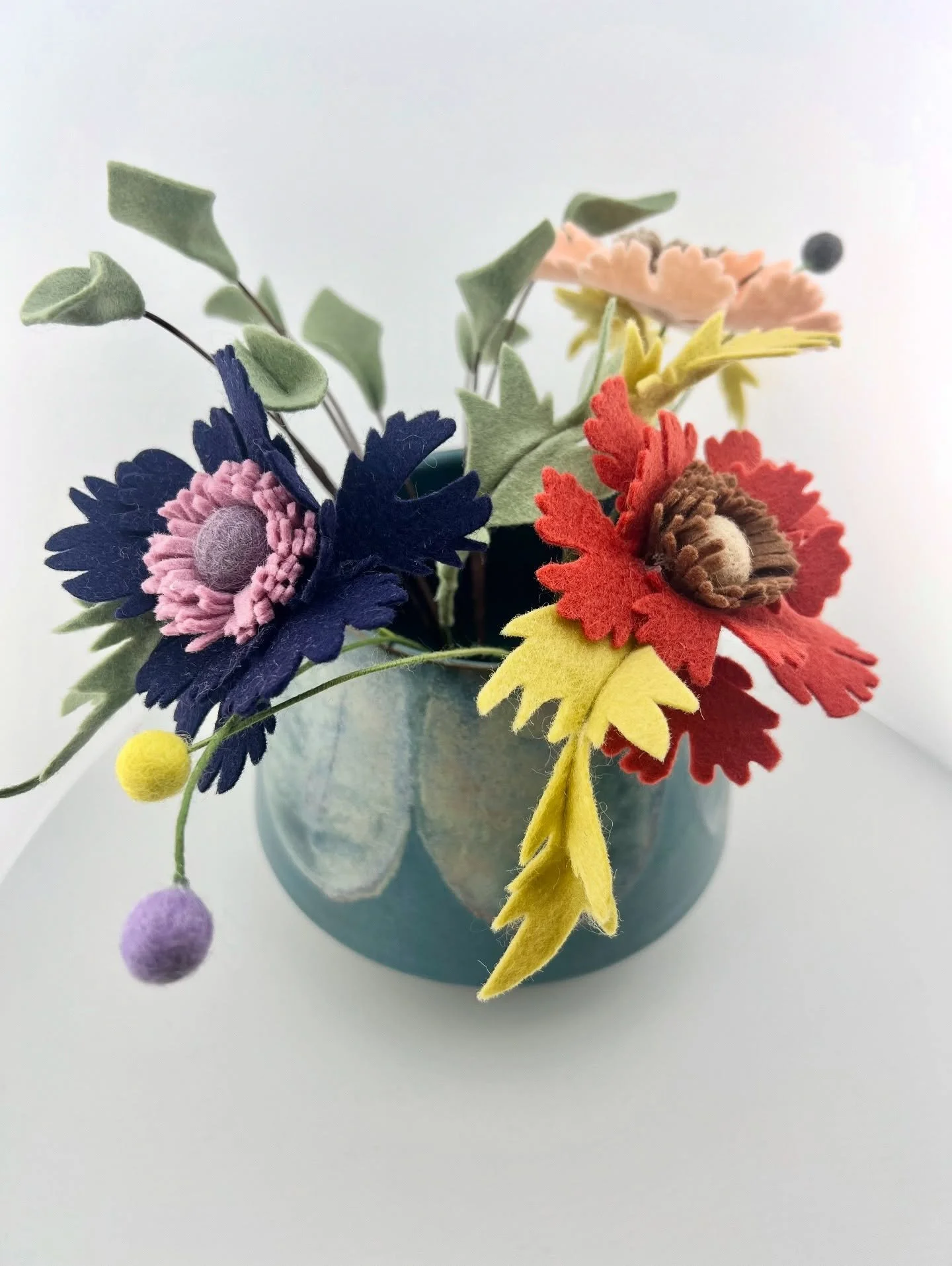 Clay and felt&mdash;two humble, natural materials, shaped by hand into something lasting. This piece began as a quiet exchange with clay: its resistance, its softness, its memory. The glaze added its own poetry&mdash;pooling and drifting into petal-l