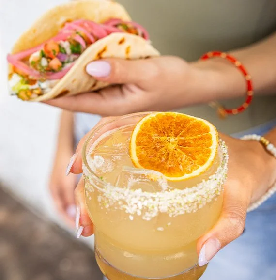 Hand holding a margarita and a taco at Taco/Social