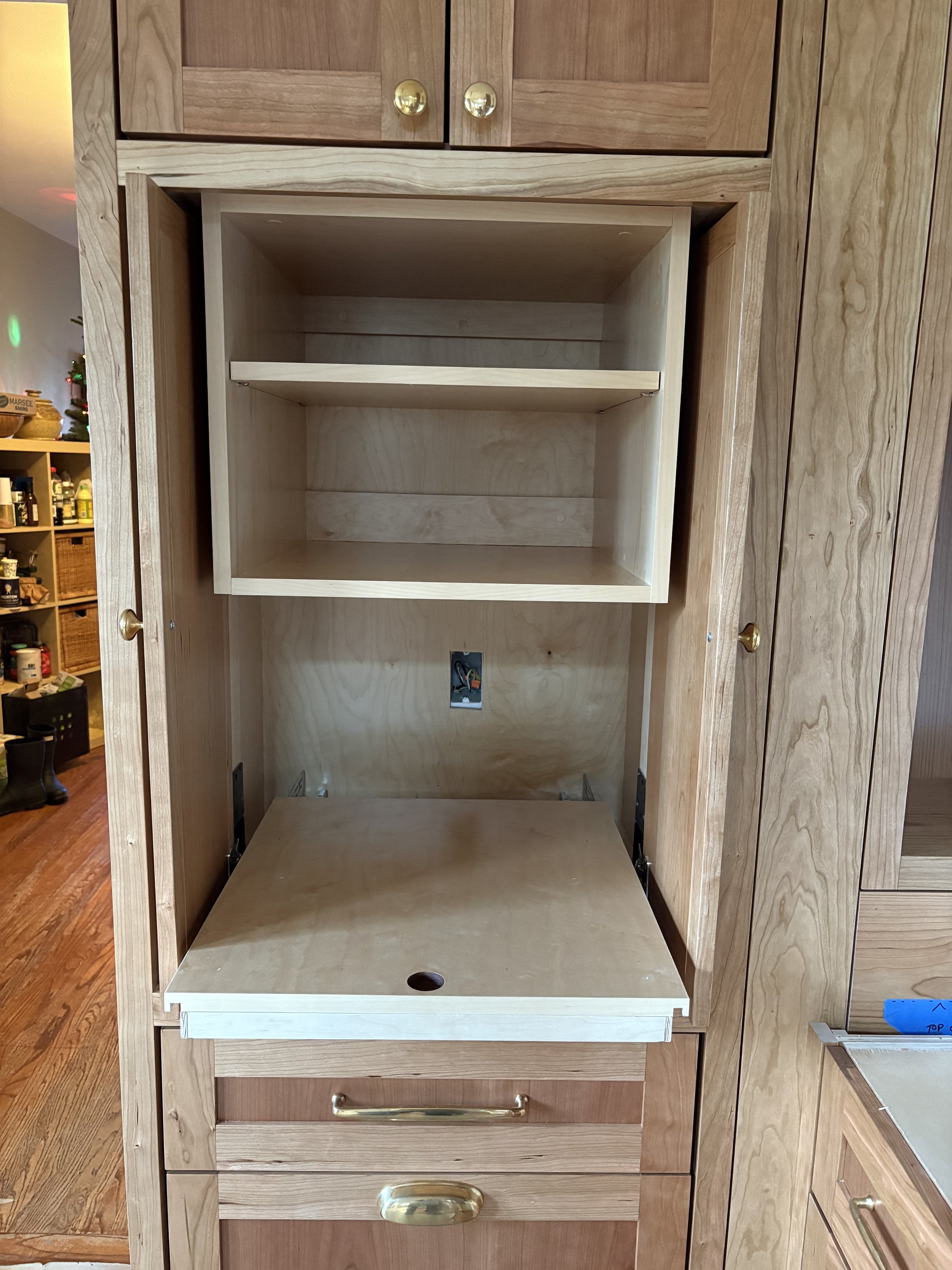 Wooden kitchen cabinet with open and closed storage compartments, some with gold-colored handles.