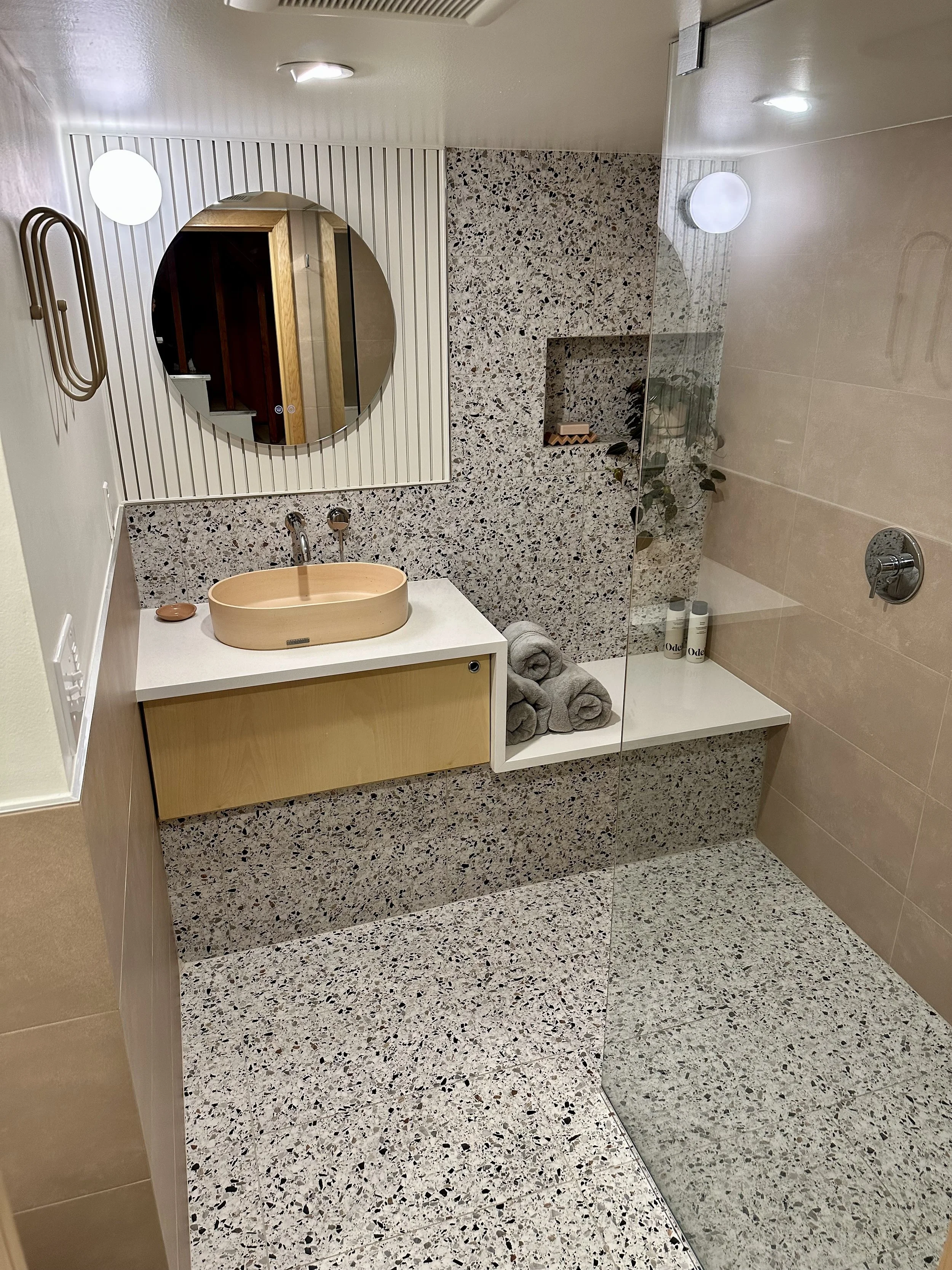 Renovated tiled bathroom with custom vanity and waterfall countertop
