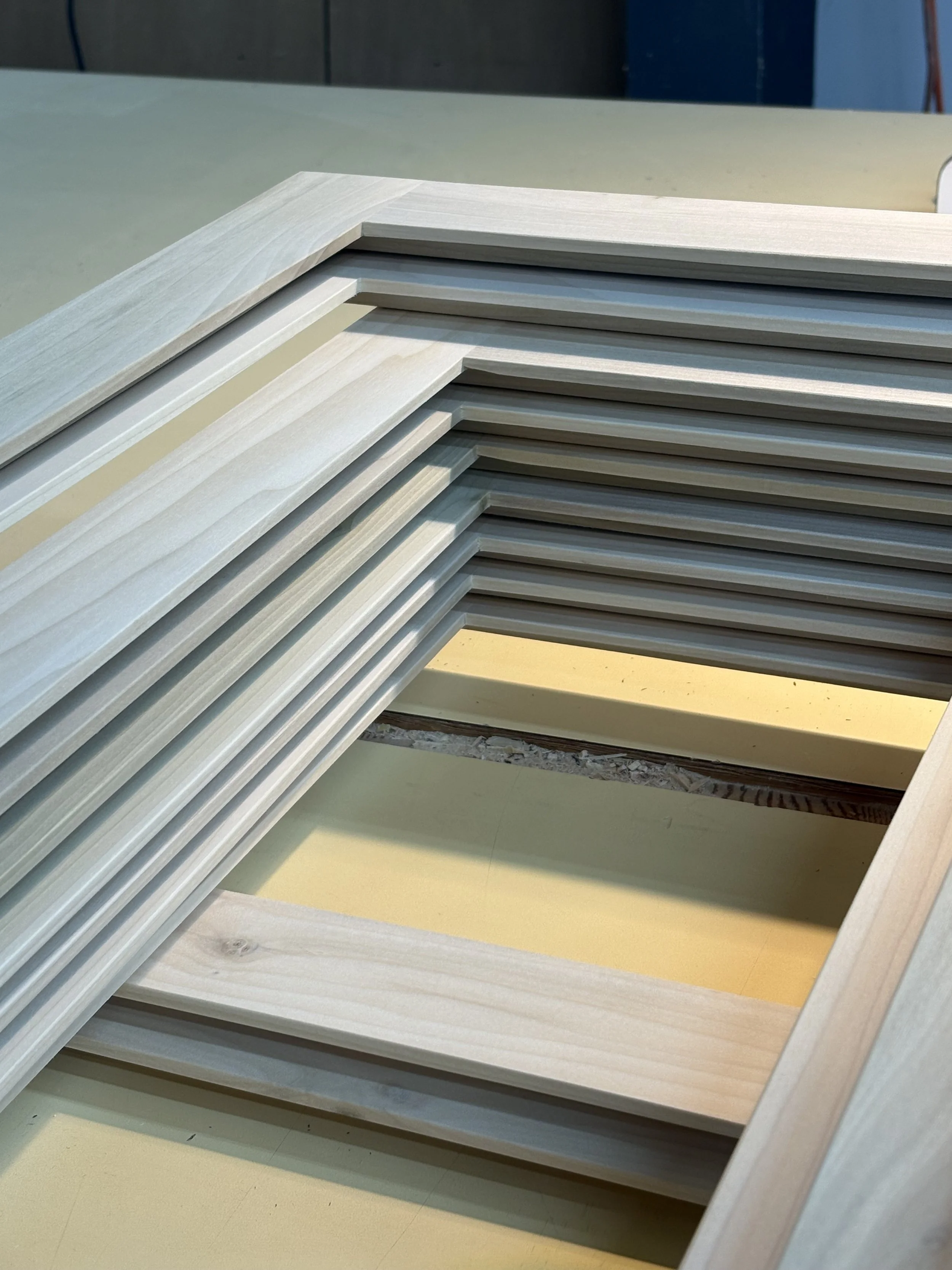 Stacked wooden frames or moldings on a light-colored surface.