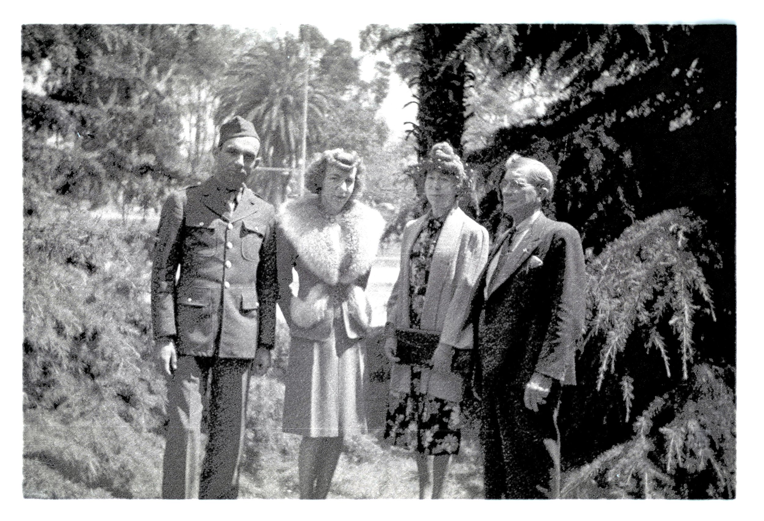 Bembridge Photo Archive Black and white photo showing four people standing outdoors among trees, including two women and two men, dressed in mid-20th century clothing.