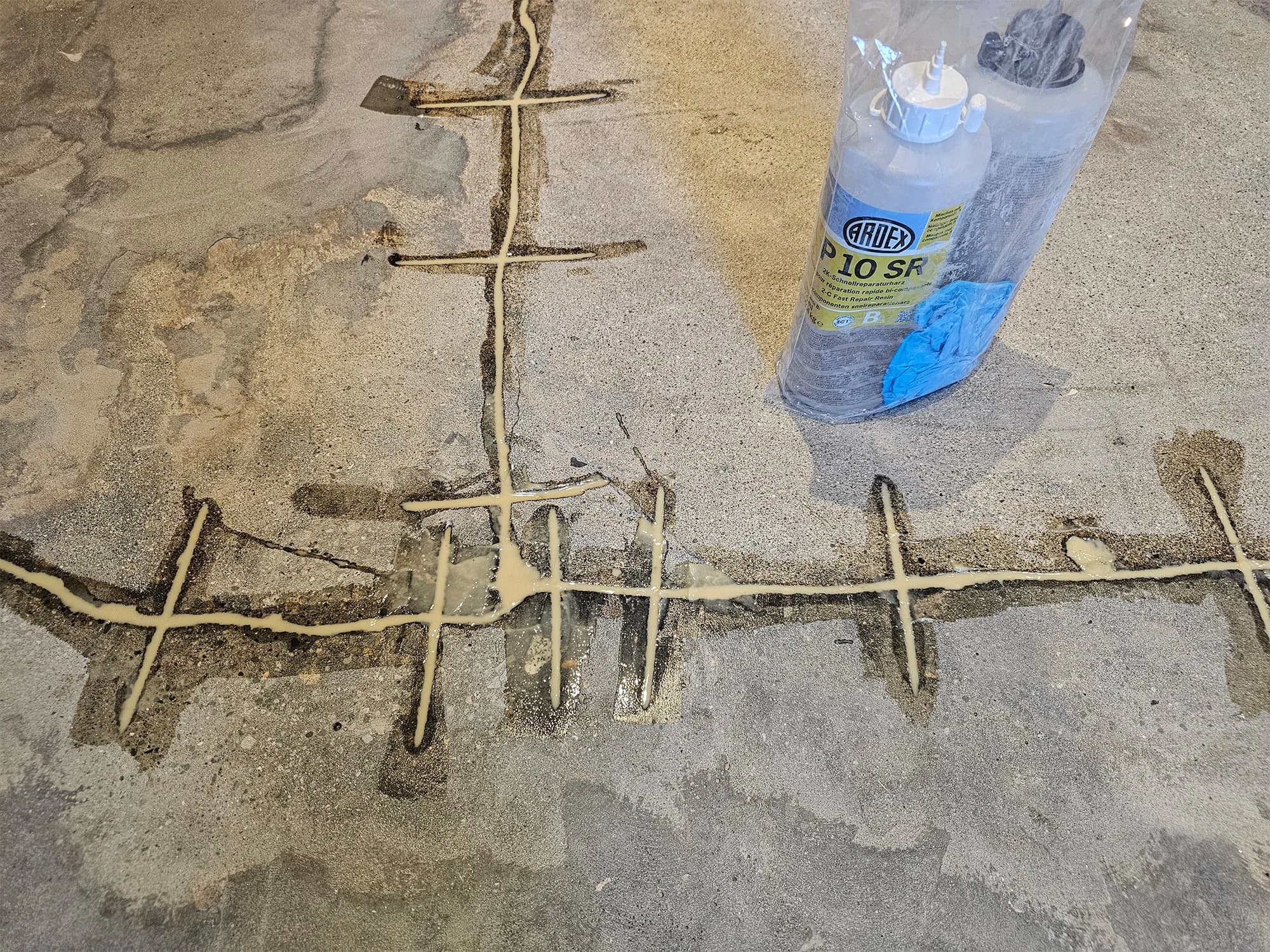 Concrete floor with chalk drawings and a plastic squeeze bottle with a blue cap and a plastic bag containing black objects.