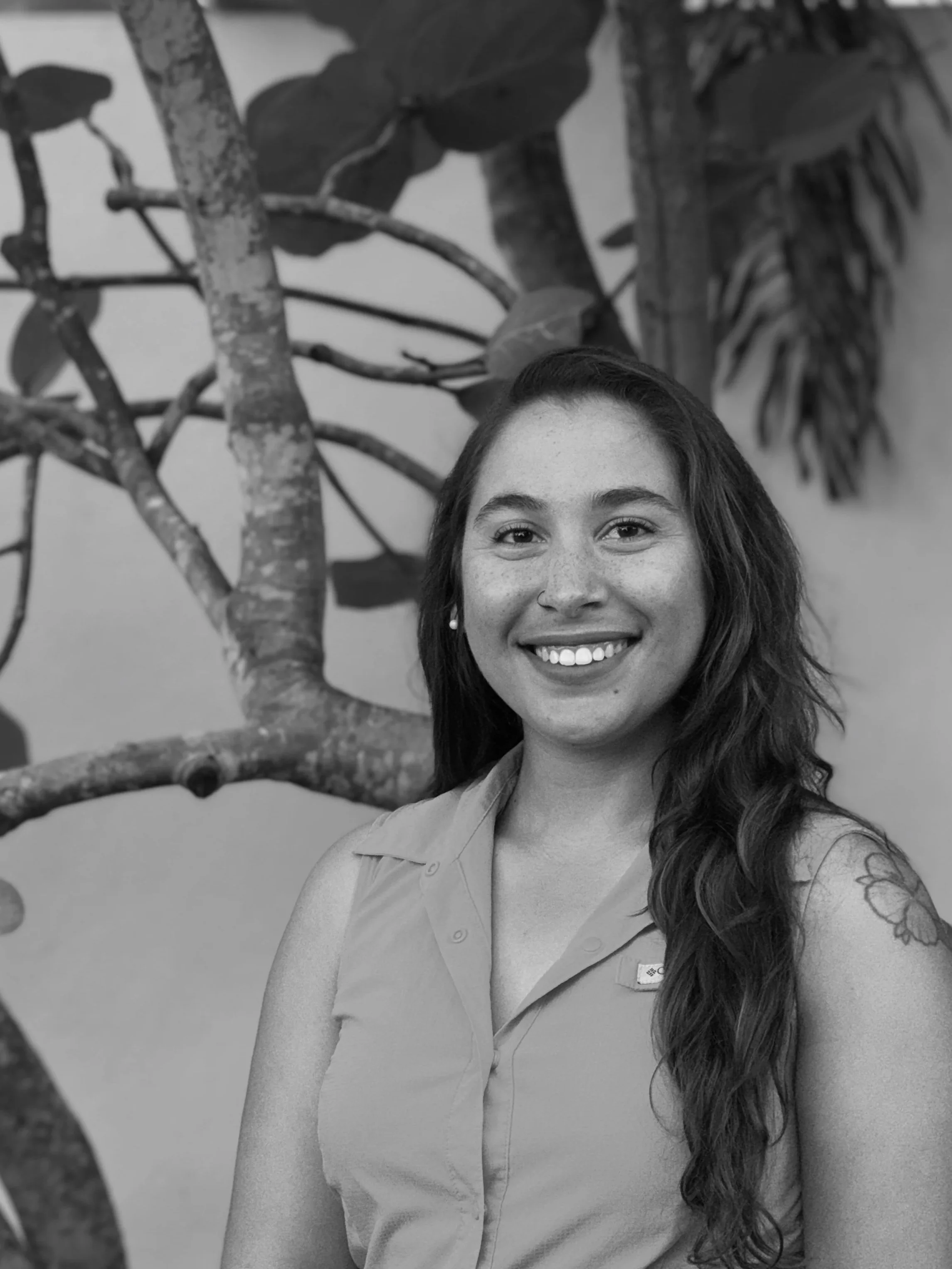 A person in scuba gear making a peace sign while floating in the ocean near a shoreline with trees.