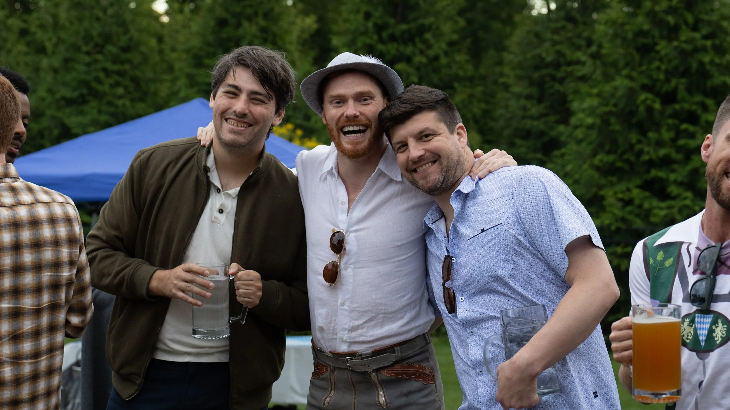 Group of friends at an outdoor event smiling and holding drinks.
