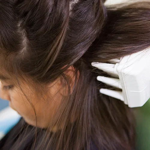 A woman getting her hair styled with a hairbrush and hair rollers