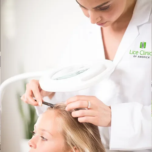 A healthcare professional examining a child's scalp with a magnifying glass at Lice Clinic of America.