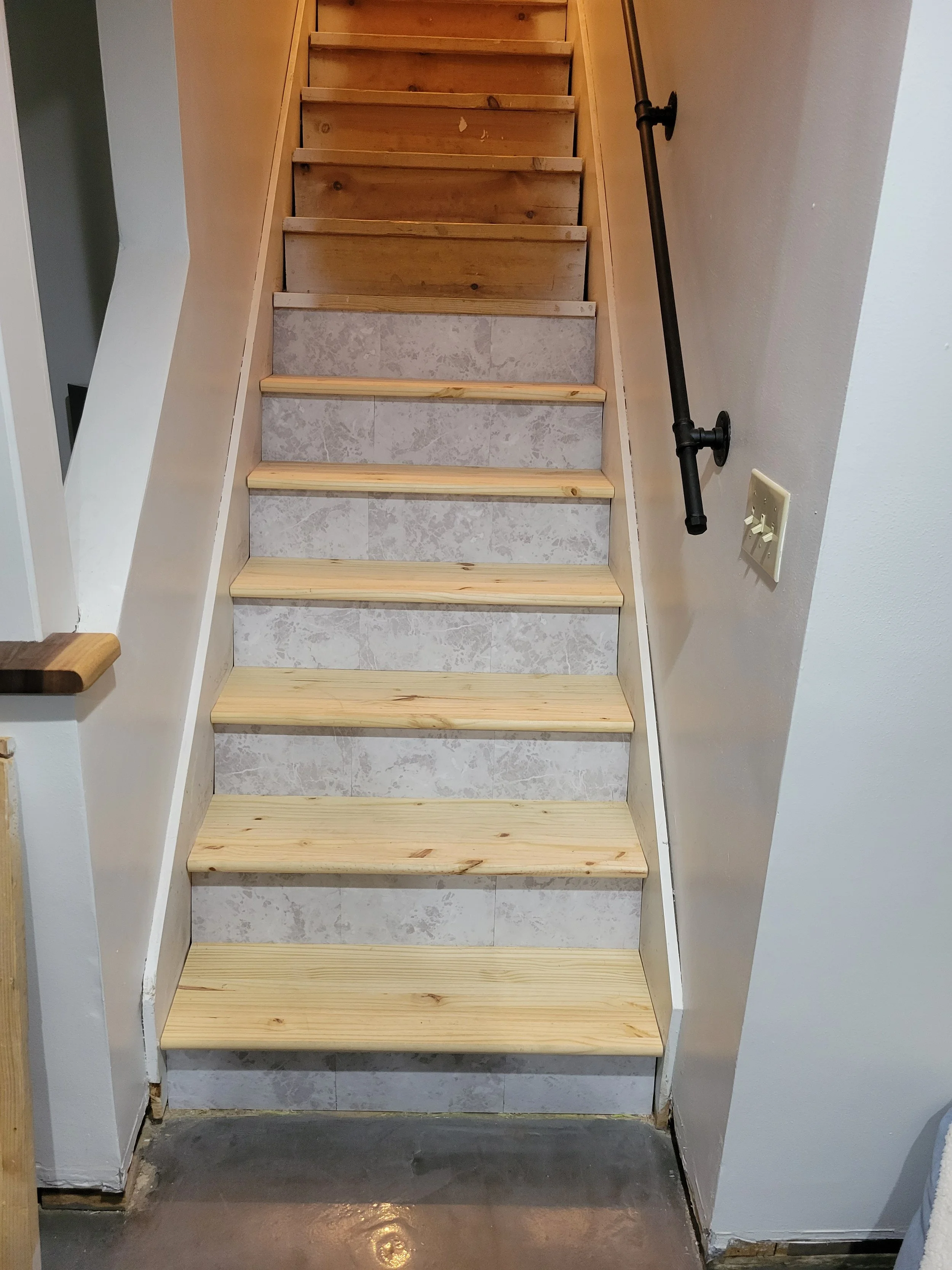 Wooden stairs with treads installed, partially finished, with outlets on the wall to the right.