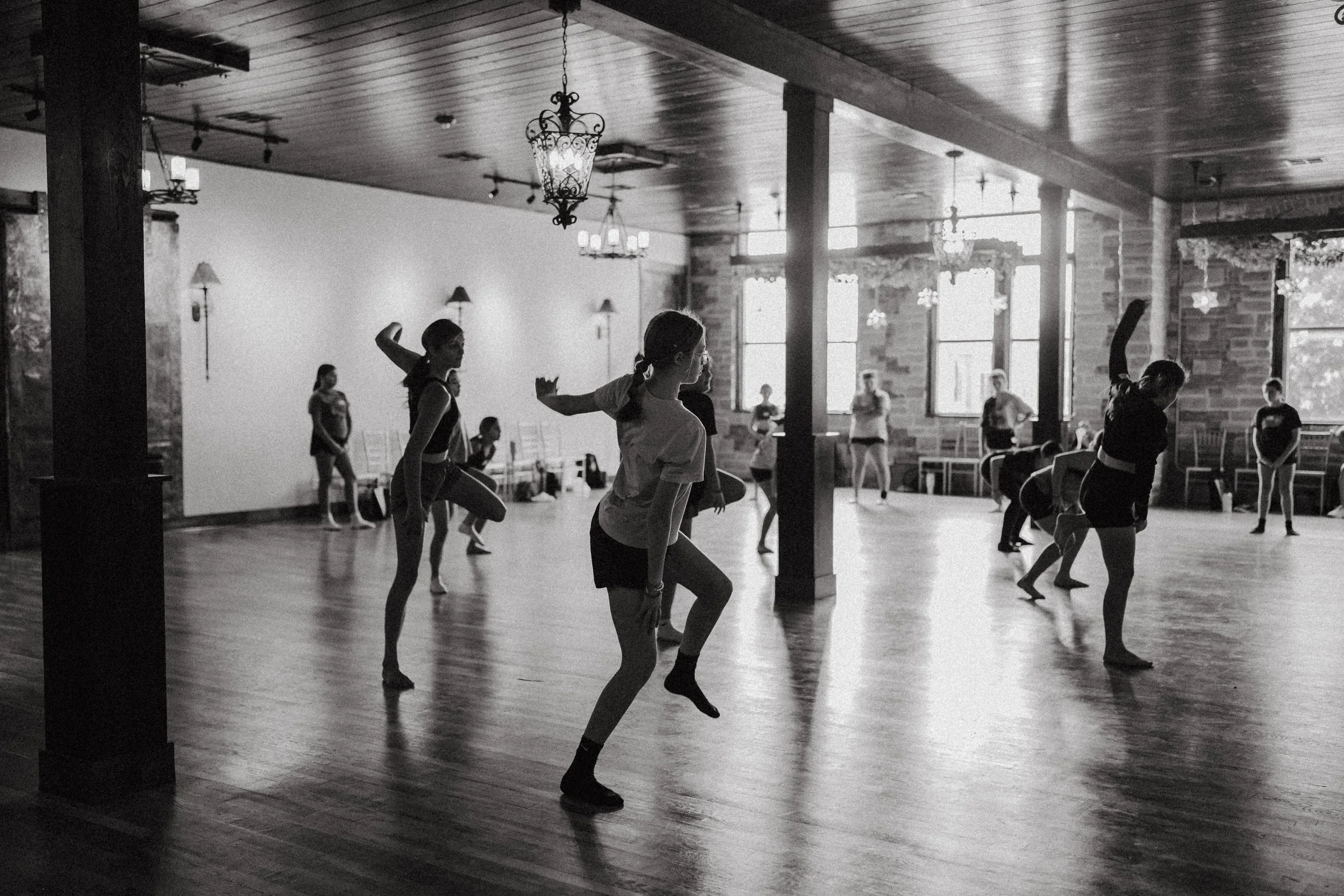 Ballet class with students practicing dance moves in a spacious, well-lit studio.