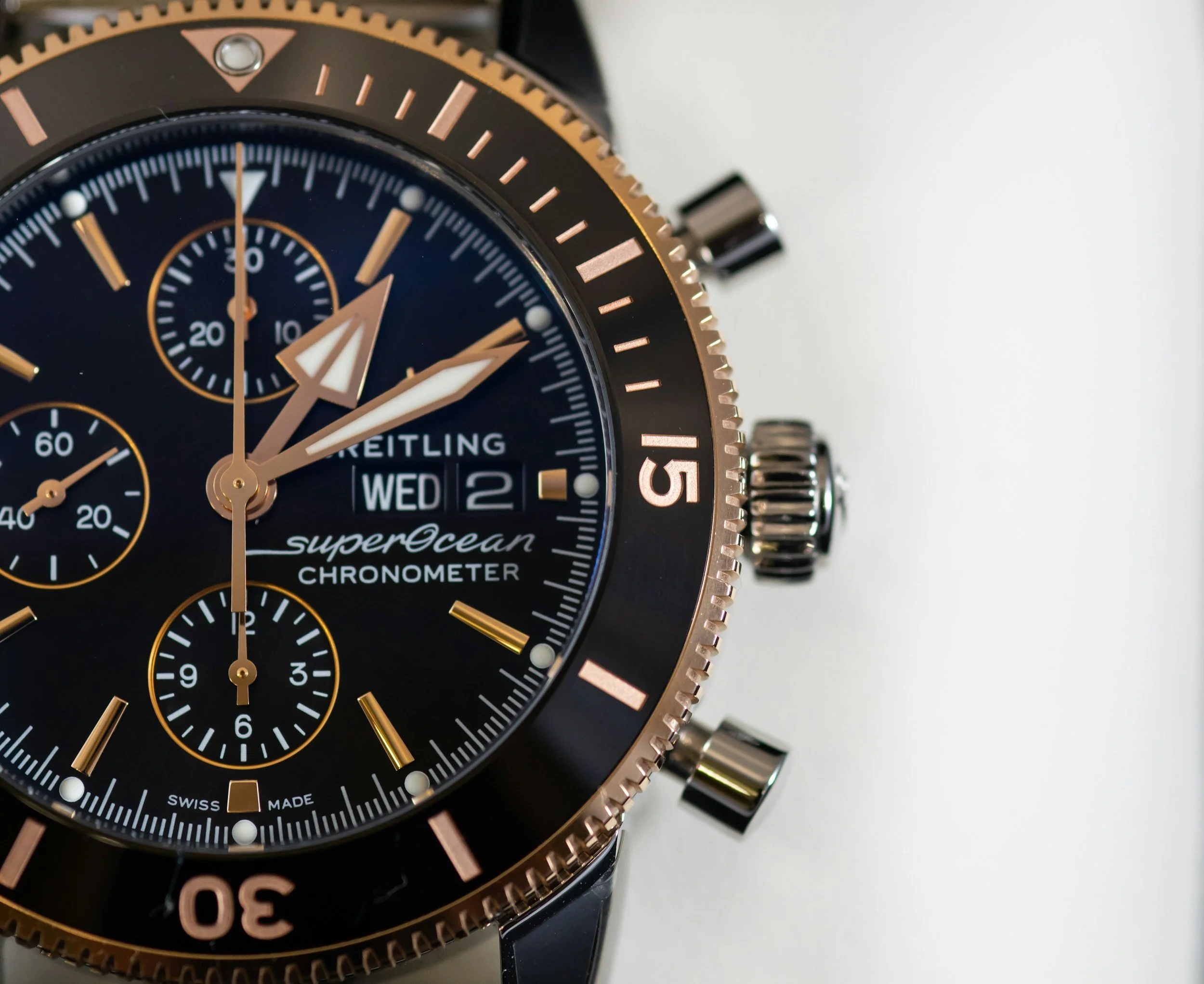 Close-up of a Breitling SuperOcean chronograph watch with black dial, gold accents, and multiple subdials showing time and date.