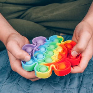 Person holding a colorful rainbow Twisty Human Pop It fidget toy.