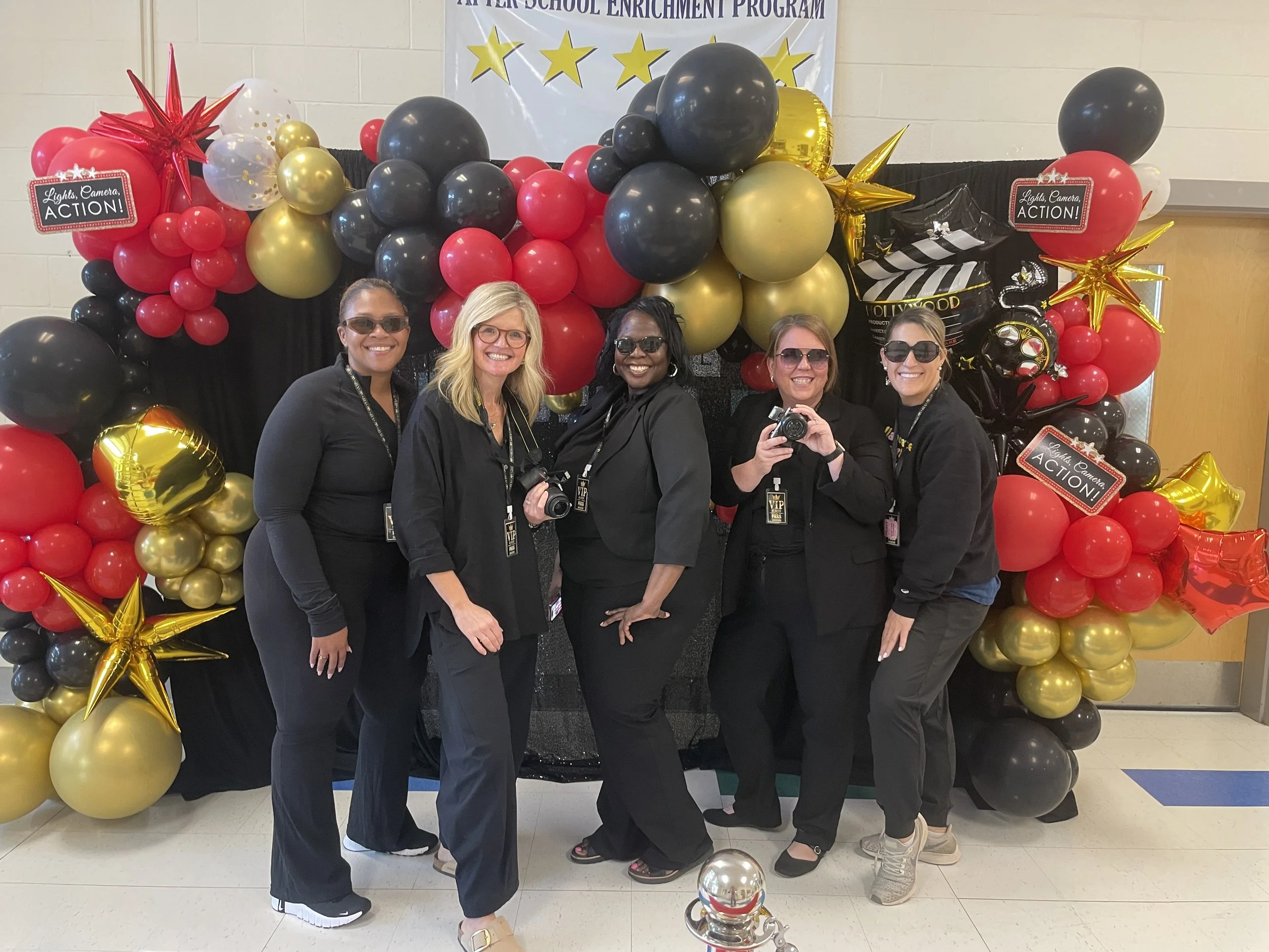 Staff members posing in front of a balloon banner.