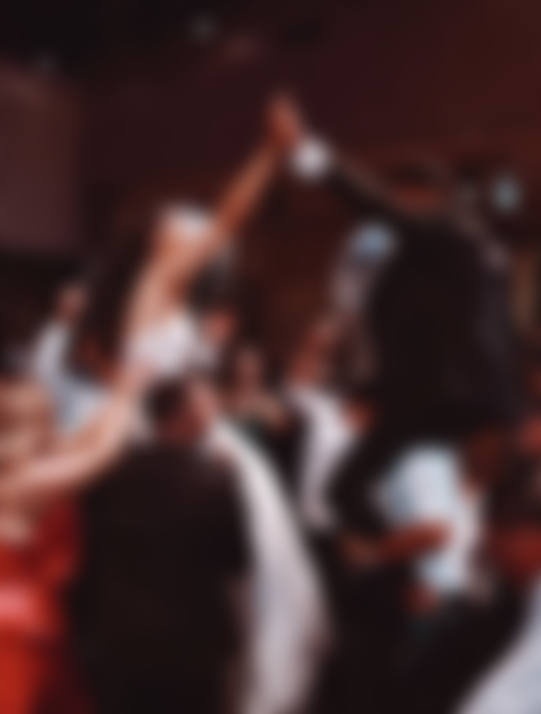 Blurry image of a group of people celebrating or toasting with a bottle in a dimly lit indoor setting.