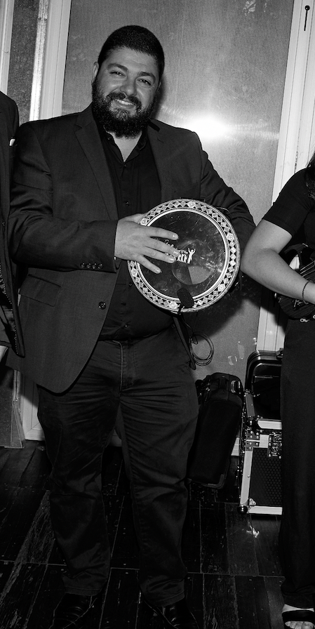 A man in a suit holding a circular award or plaque, smiling at the camera.