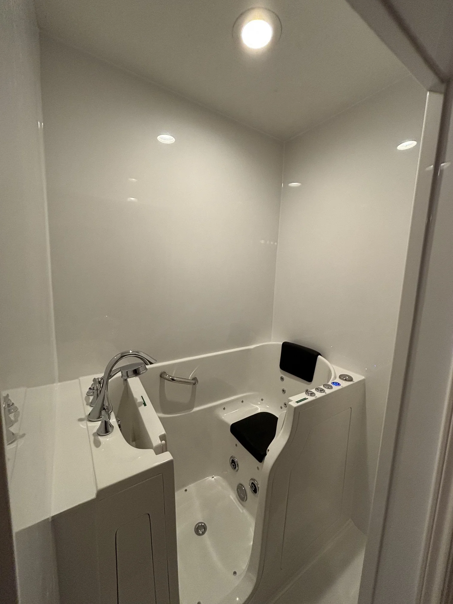white walk-in bathtub for accessibility, with grab bars and a slide bar.