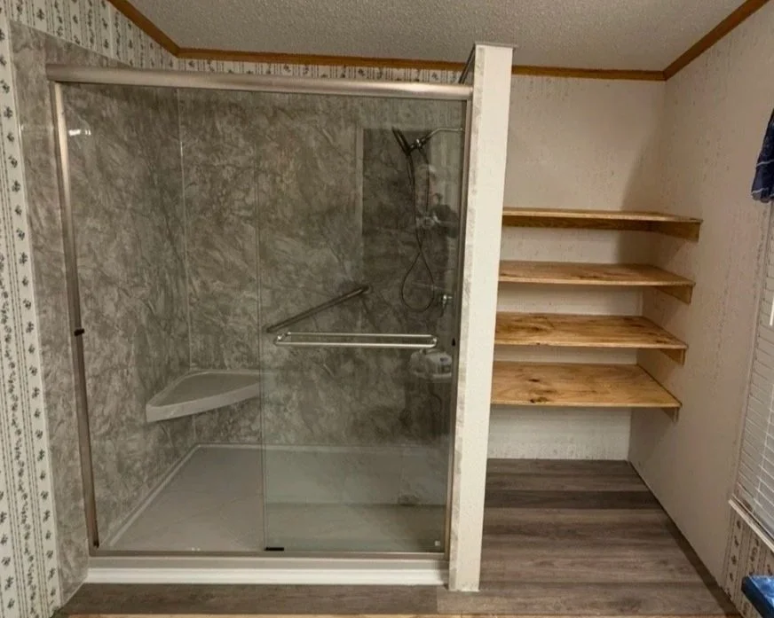 Bathroom with shower on the left and open linen closet on the right.