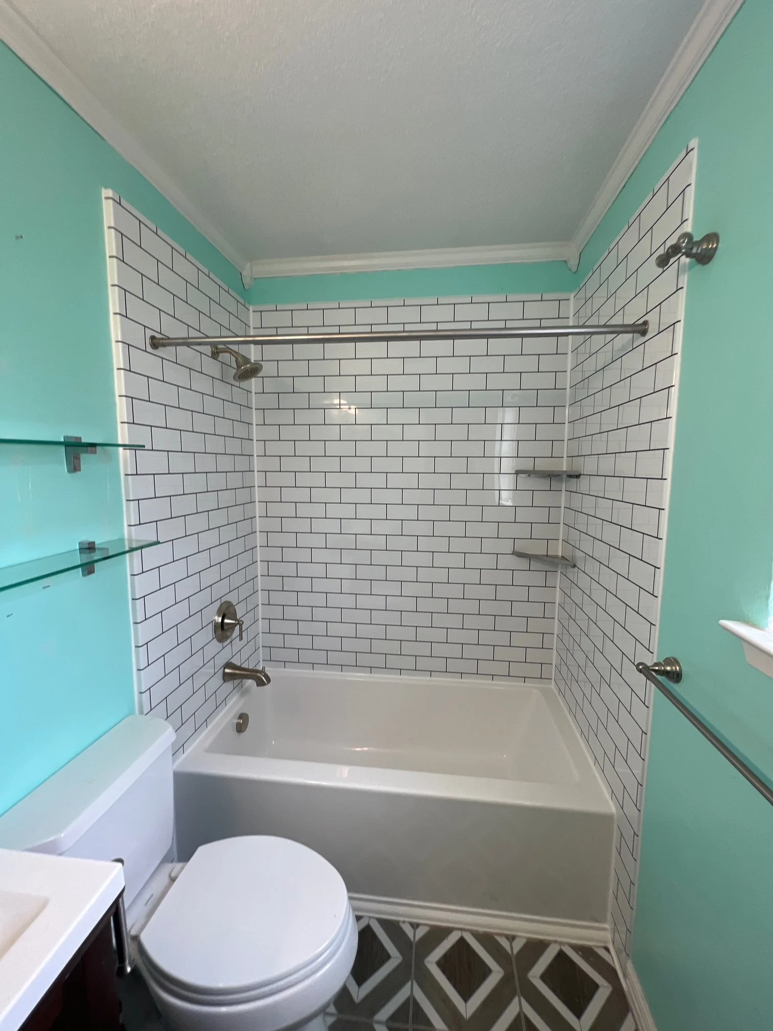 Bathroom with light blue walls and white subway tile shower wall. Shower has a silver rod, shower head, and four corner shelves.