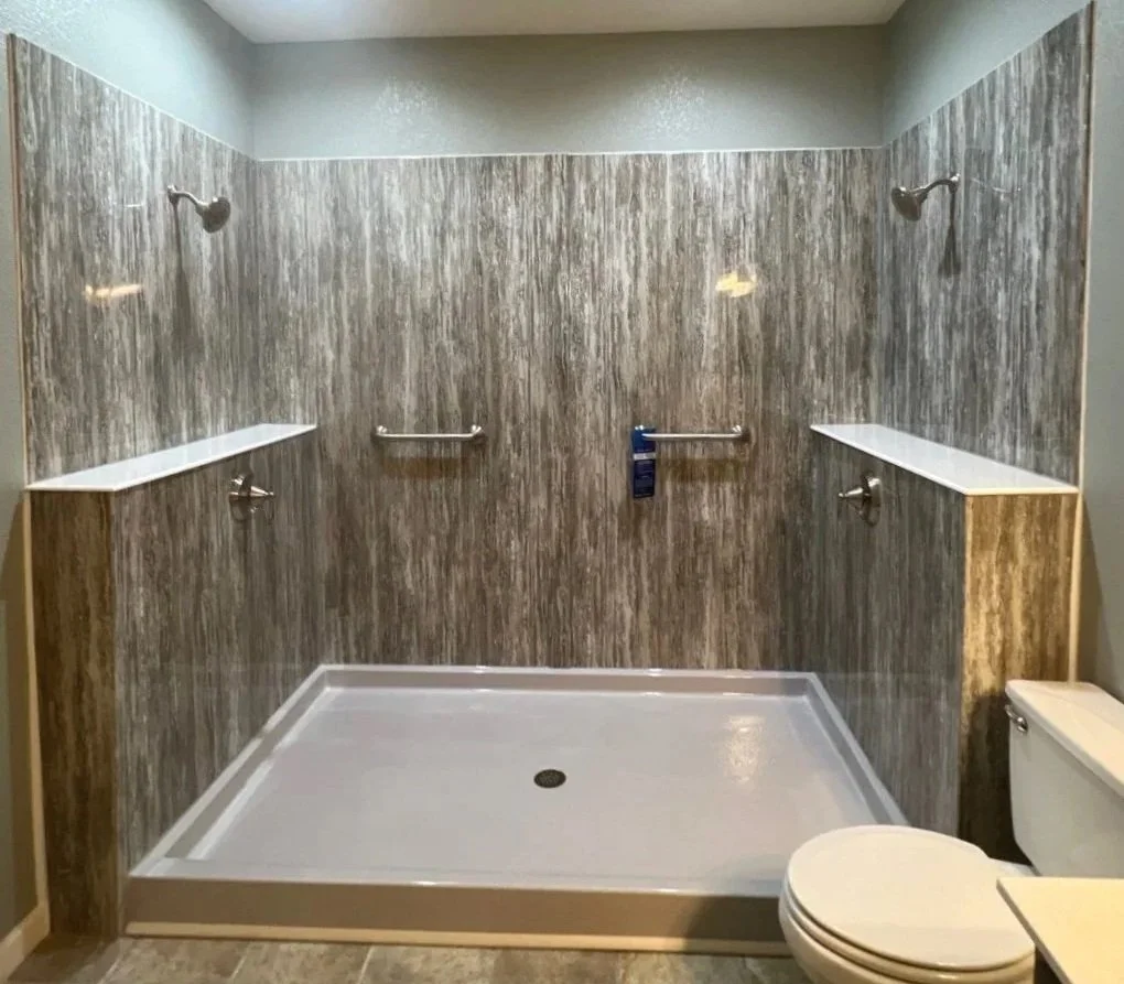 A Brown acrylic walk-in shower with a square base, wall-mounted grab bars, shelves, and multiple showerheads.