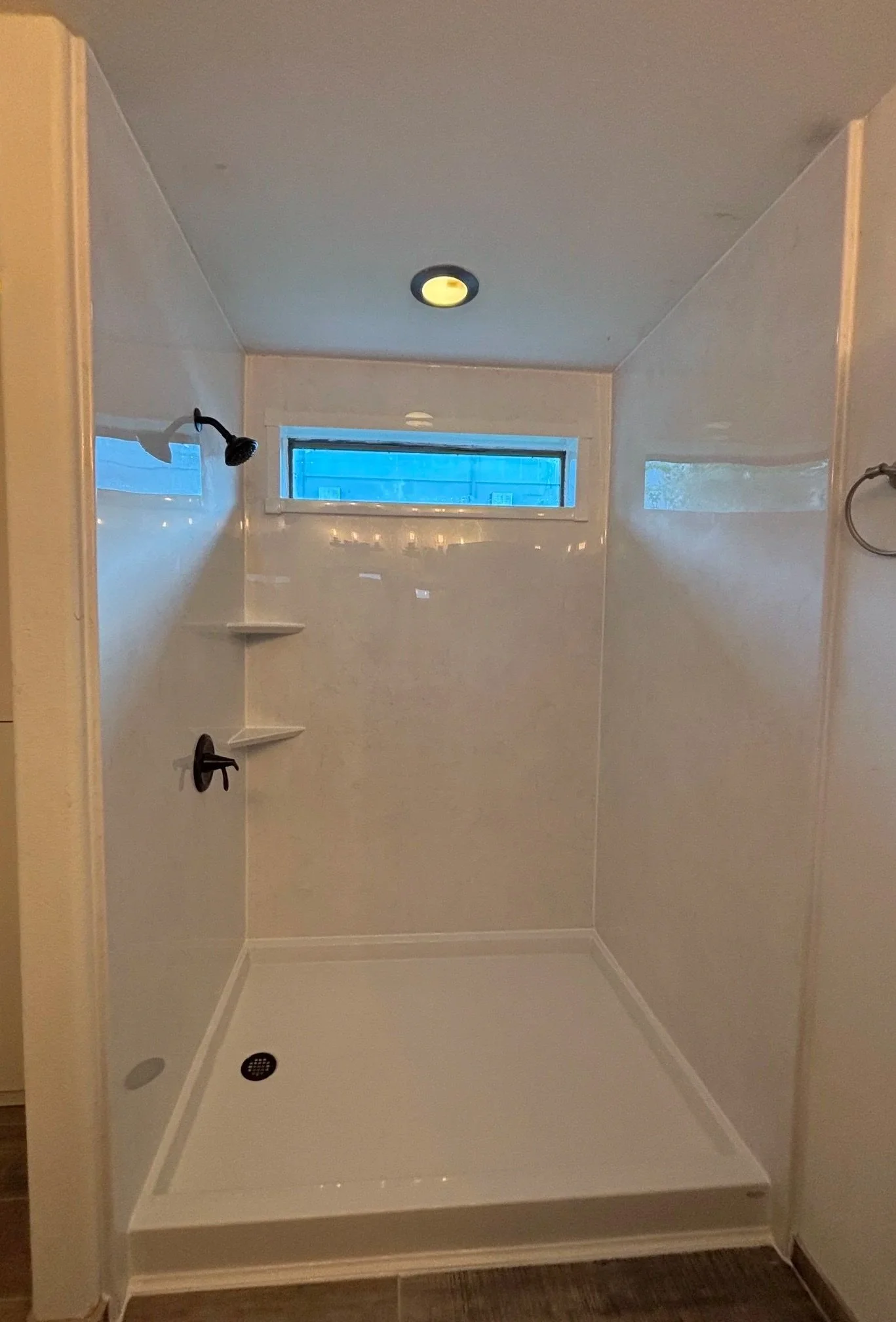 A Brown acrylic walk-in shower with a square base, wall-mounted grab bars, shelves, and multiple showerheads.