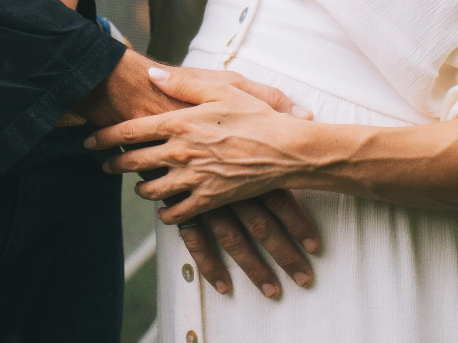 Close-up of two people holding hands, one with darker skin and the other with lighter skin, fingers intertwined