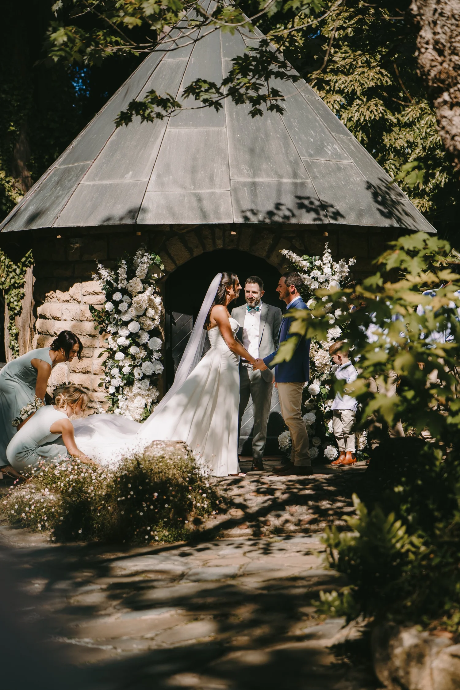 Bride walking beneath the trees in her veil