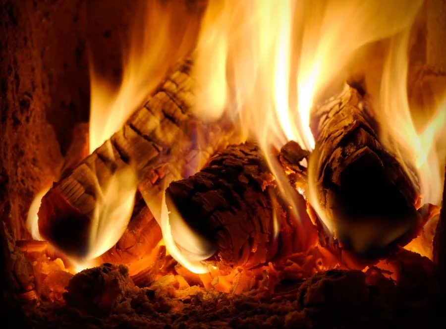 Close-up of burning logs with bright orange and yellow flames.