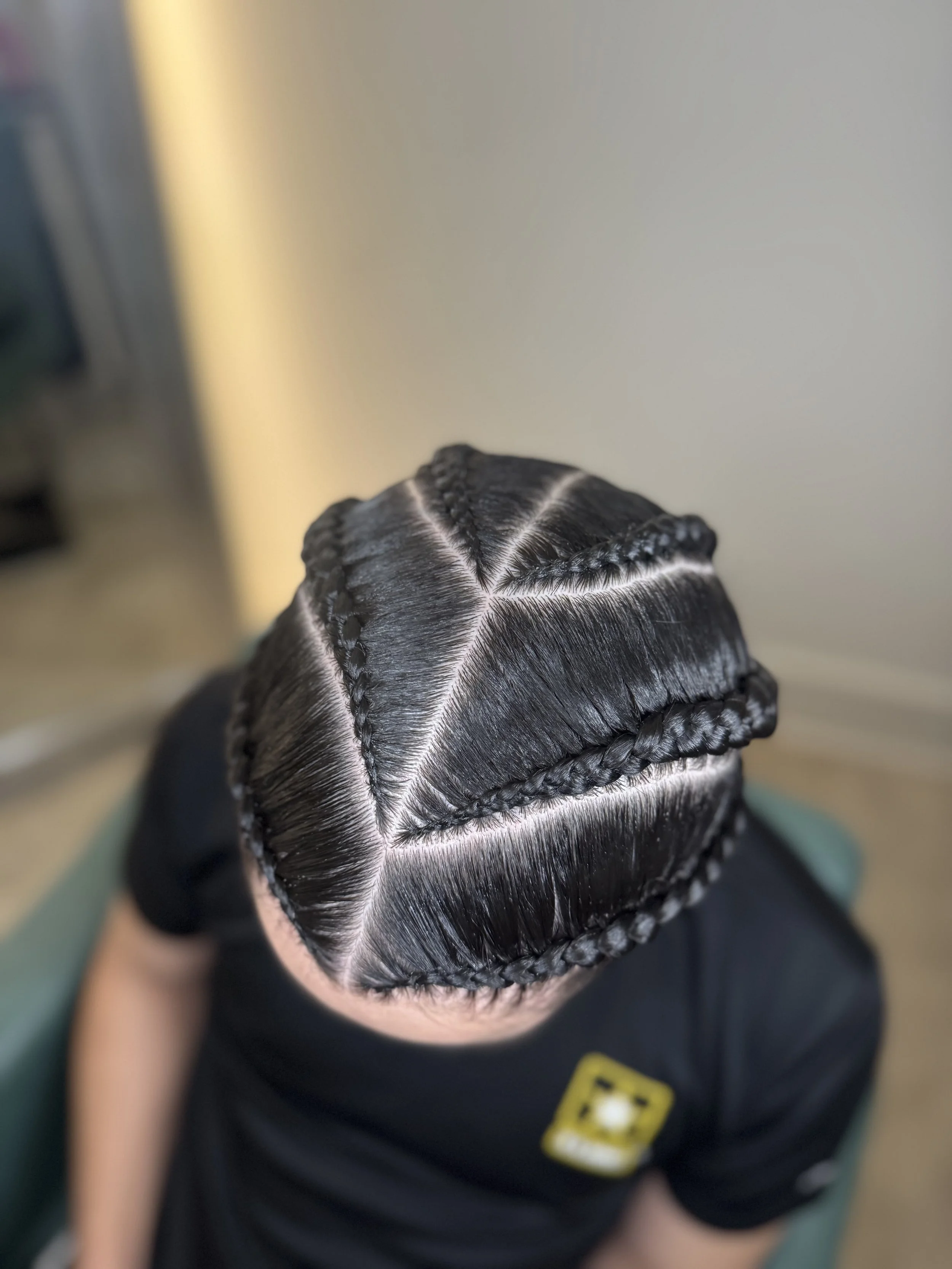 Top view of a person with freshly braided hair, showing intricate 6 cornrow hairstyles that are sleek and shiny.
