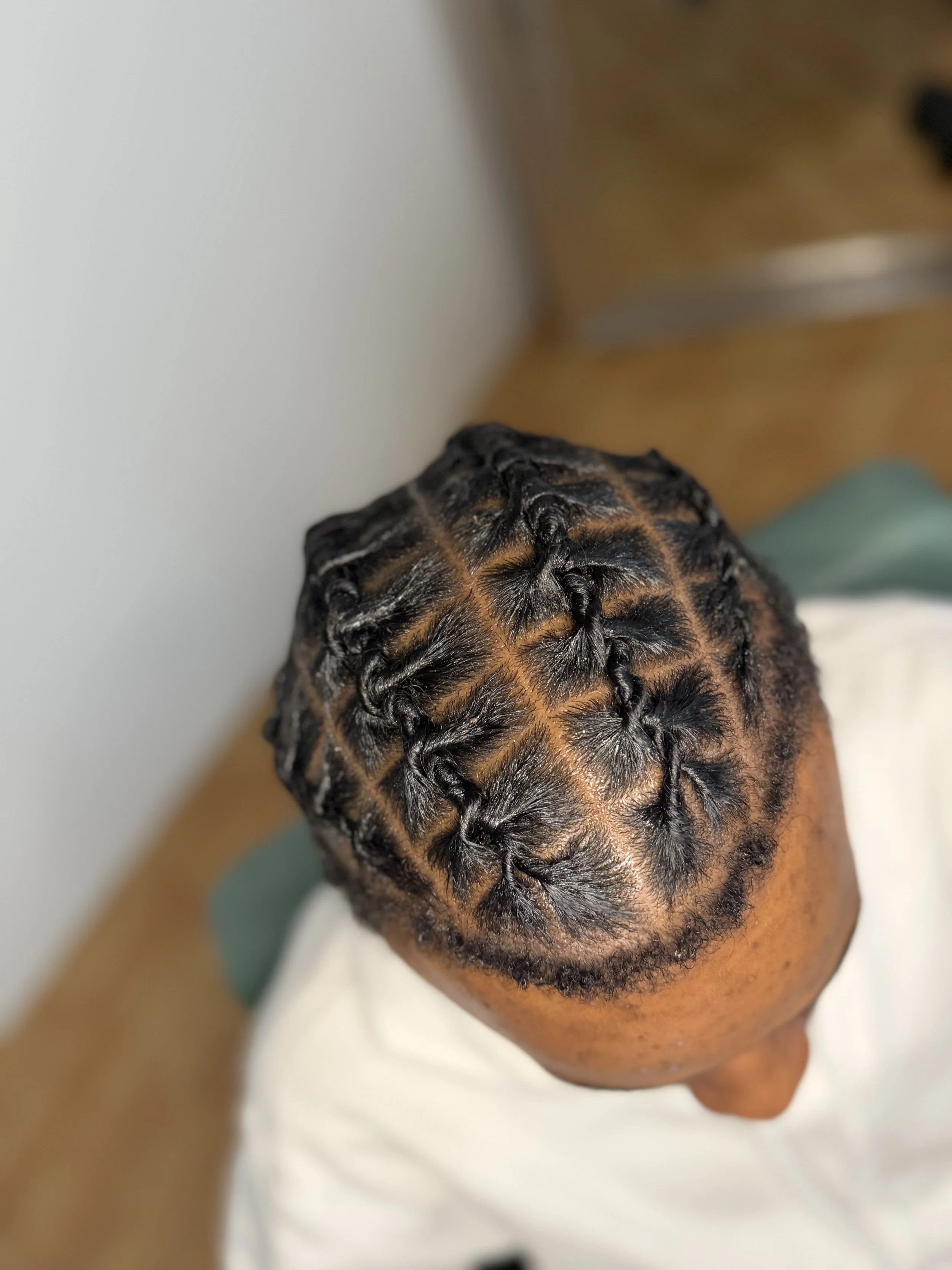 Top view of a person's head showcasing a freshly done African-American hairstyle barrel twists with neat, intricate twists and partings into 4 rows