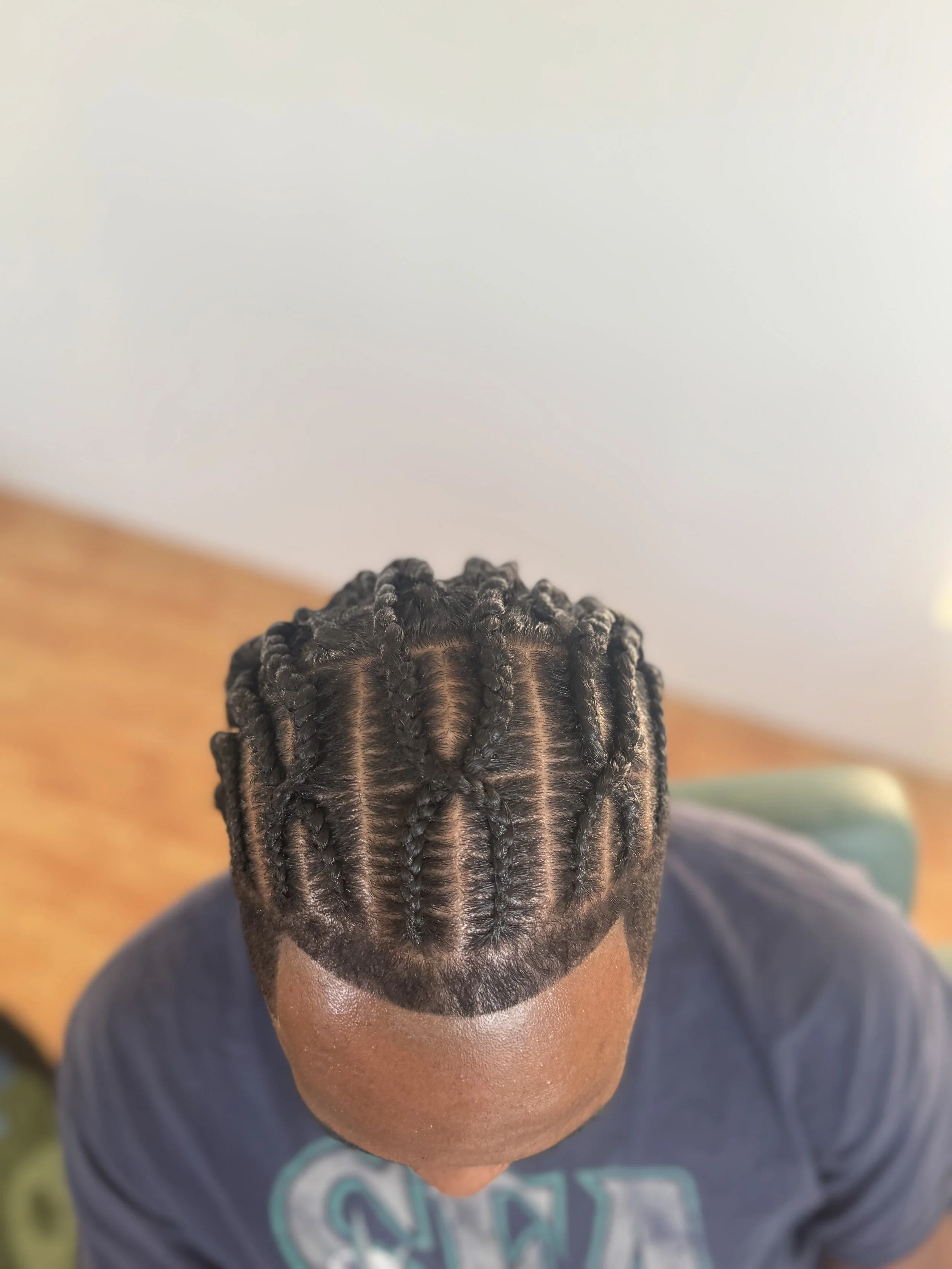 Top view of a person with neatly fulanis with a helix cross design into a two strand twist