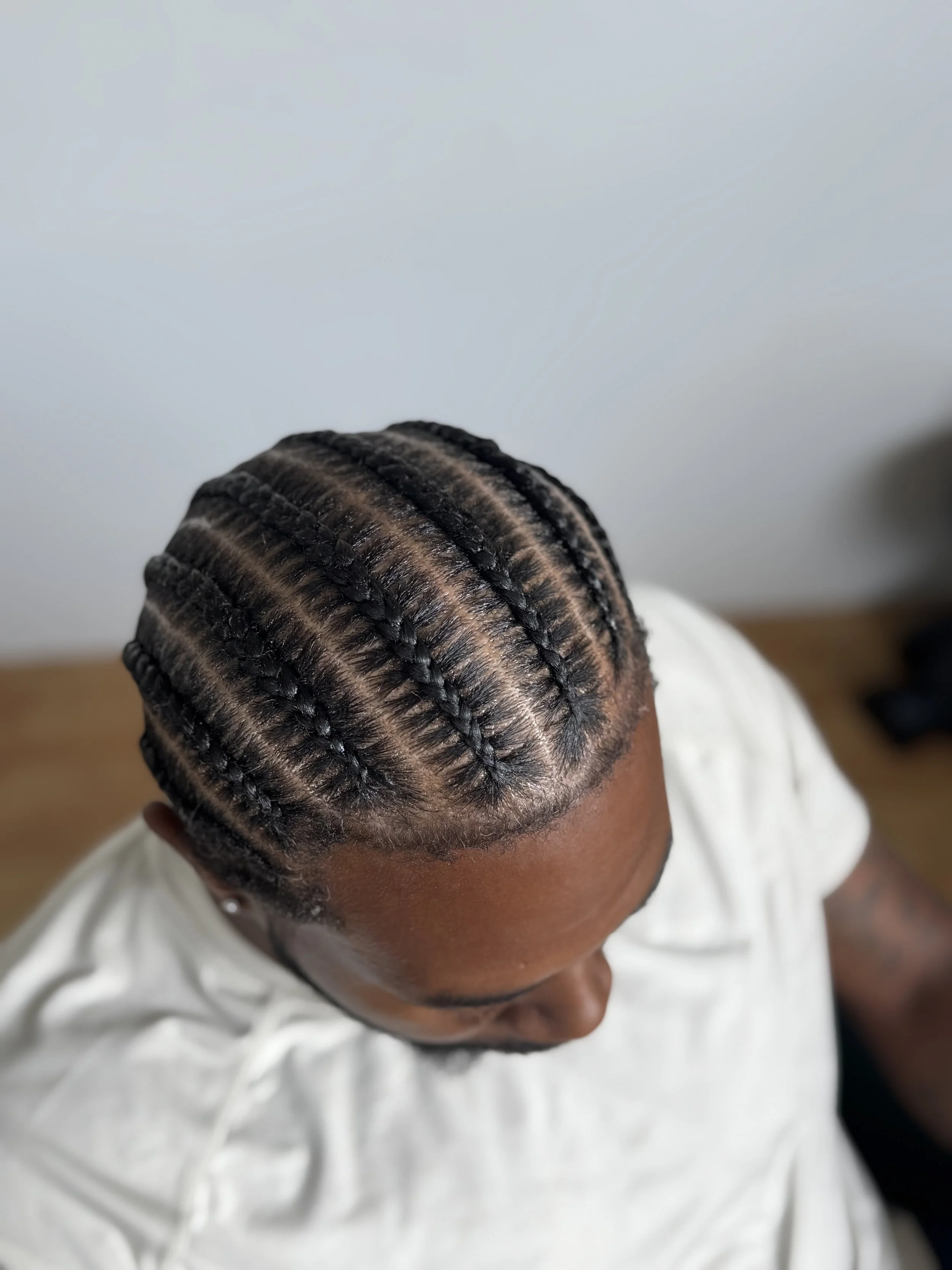 A person with dark hair styled in neat 8 cornrows.