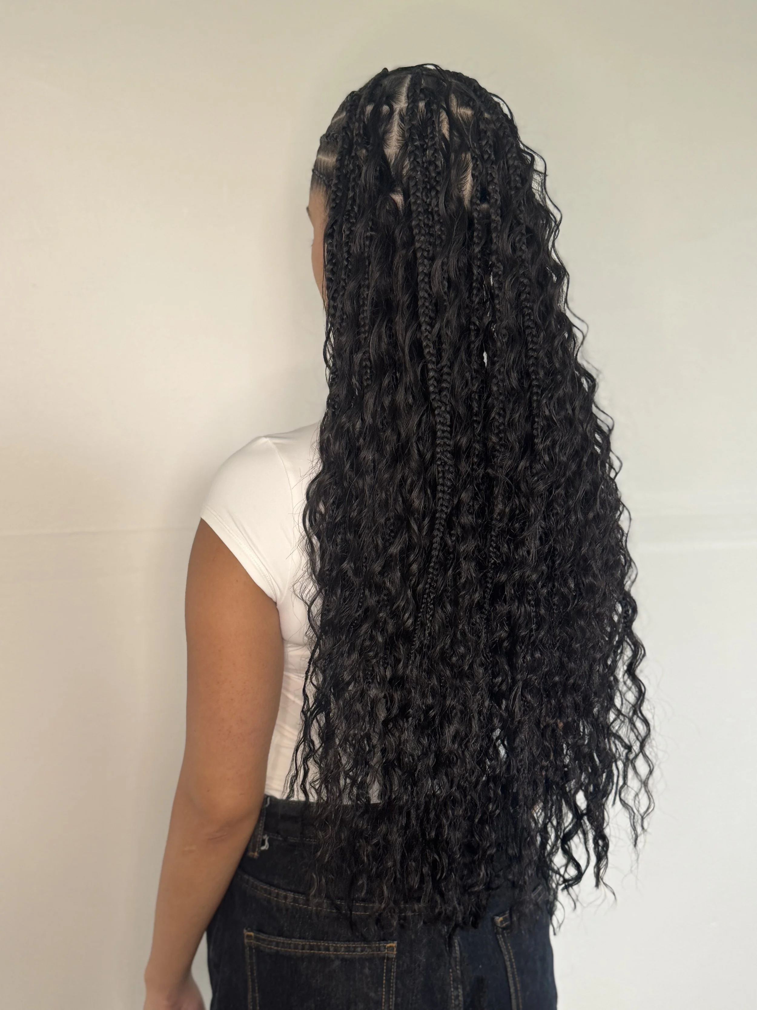 Back view of woman with long, curly, and braided knotless boho hair