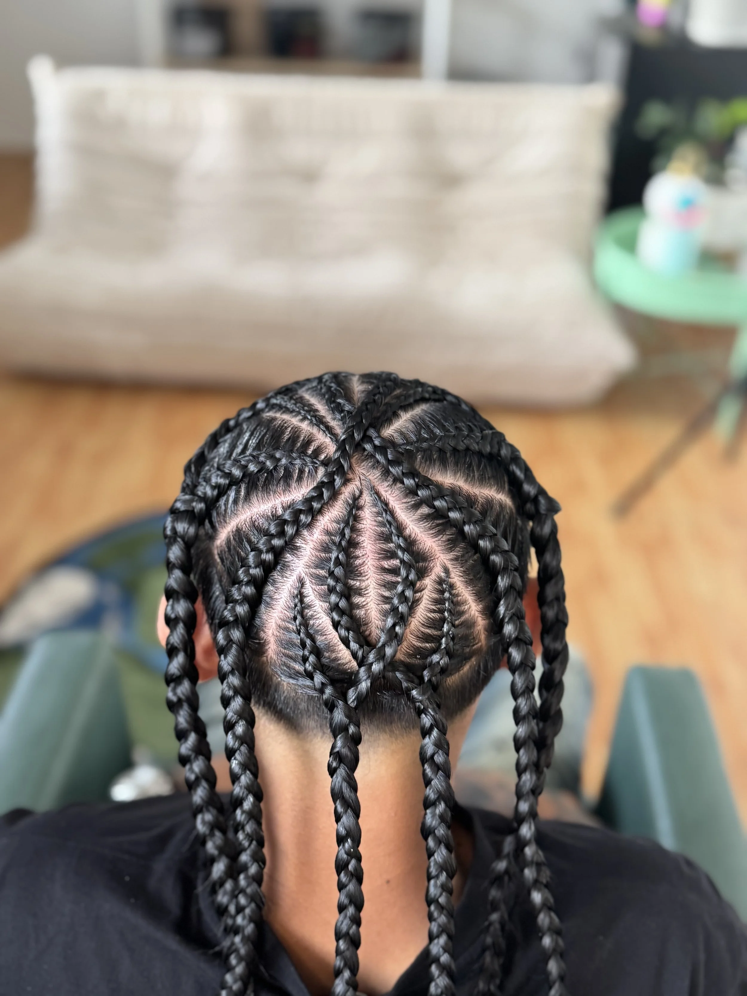 Top view of a person's head with freshly braided stitch cornrows featuring a diamond pattern, with the scalp visible and clean hair lines.