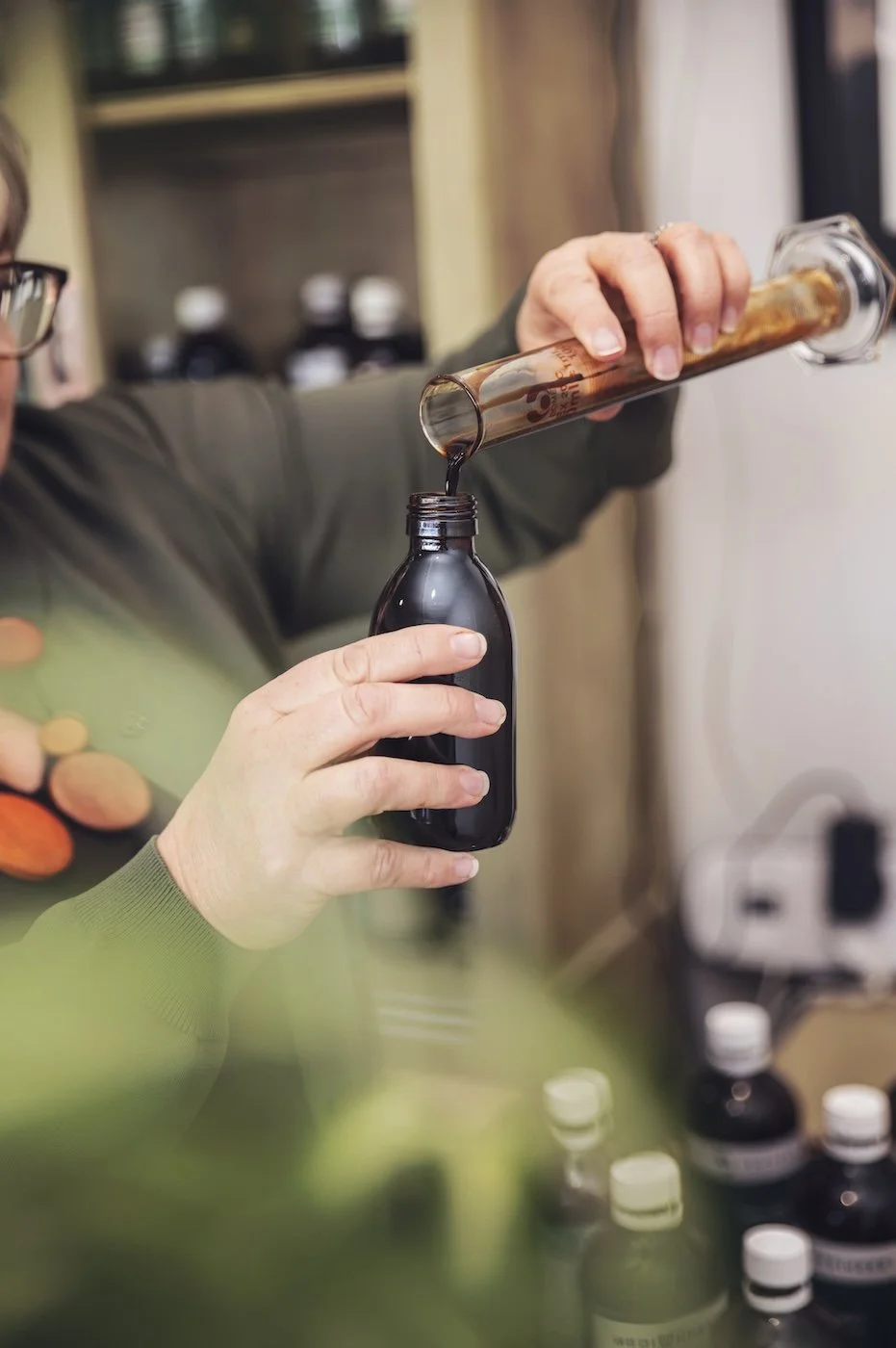 Measuring and bottling a custom herbal liquid remedy at The Herbary in Pukekohe, Auckland, showcasing in-house herbal medicine preparation and naturopathic care.