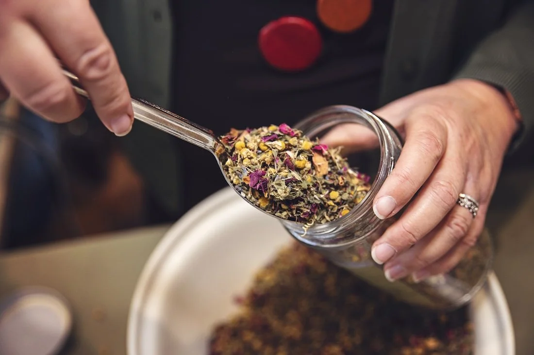 Scooping dried herbal tea blend at The Herbary in Pukekohe, Auckland, highlighting custom herbal teas and natural medicine prepared in the clinic dispensary.