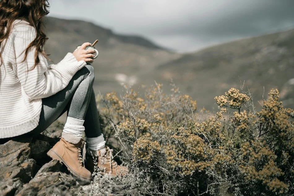 Woman resting in nature with a warm drink, reflecting balance, restoration, and holistic wellbeing supported by The Herbary naturopathic clinic in Pukekohe, Auckland.